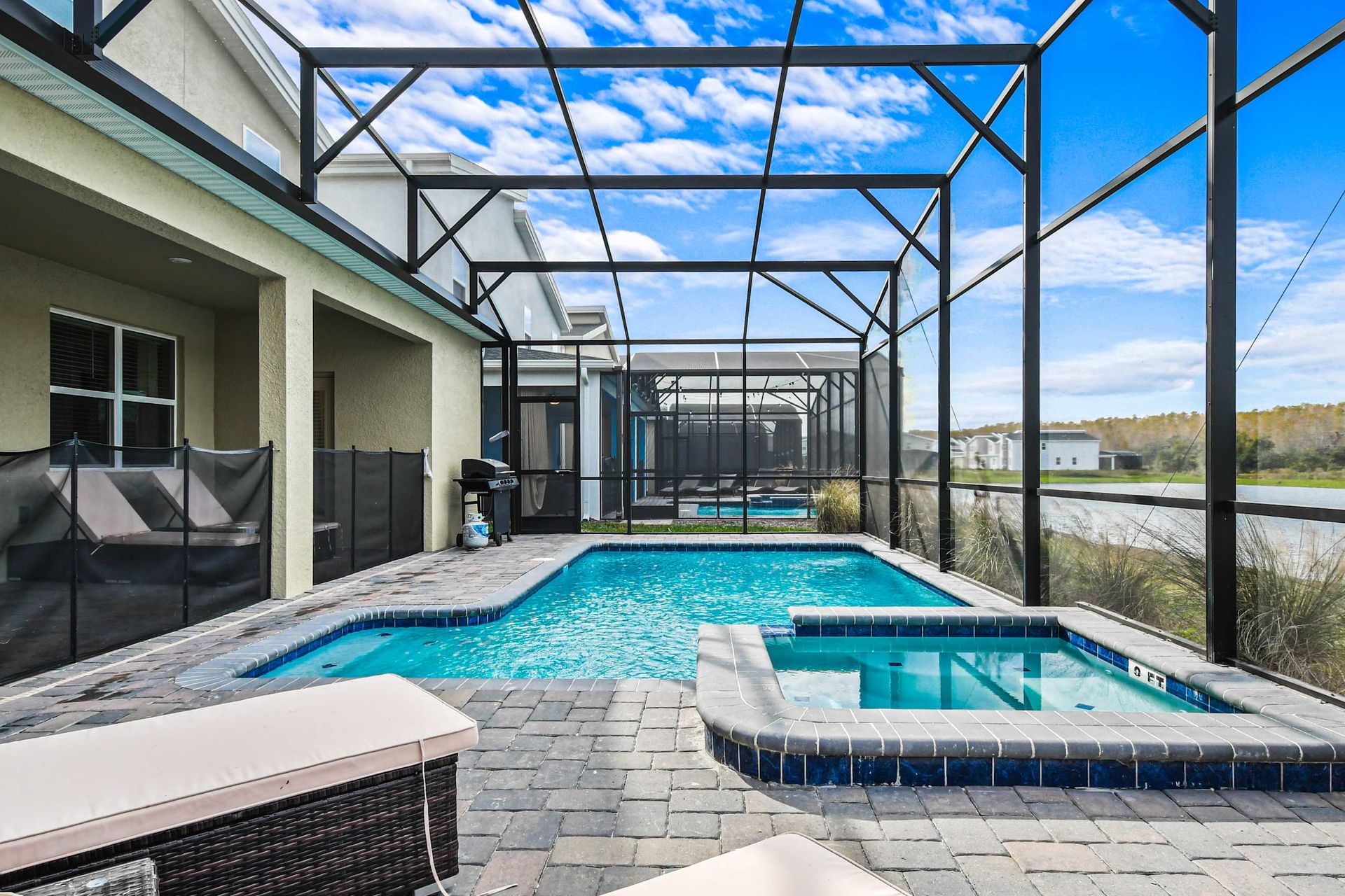 Private screened pool and spa with lake views, grill, and relaxing sun loungers.