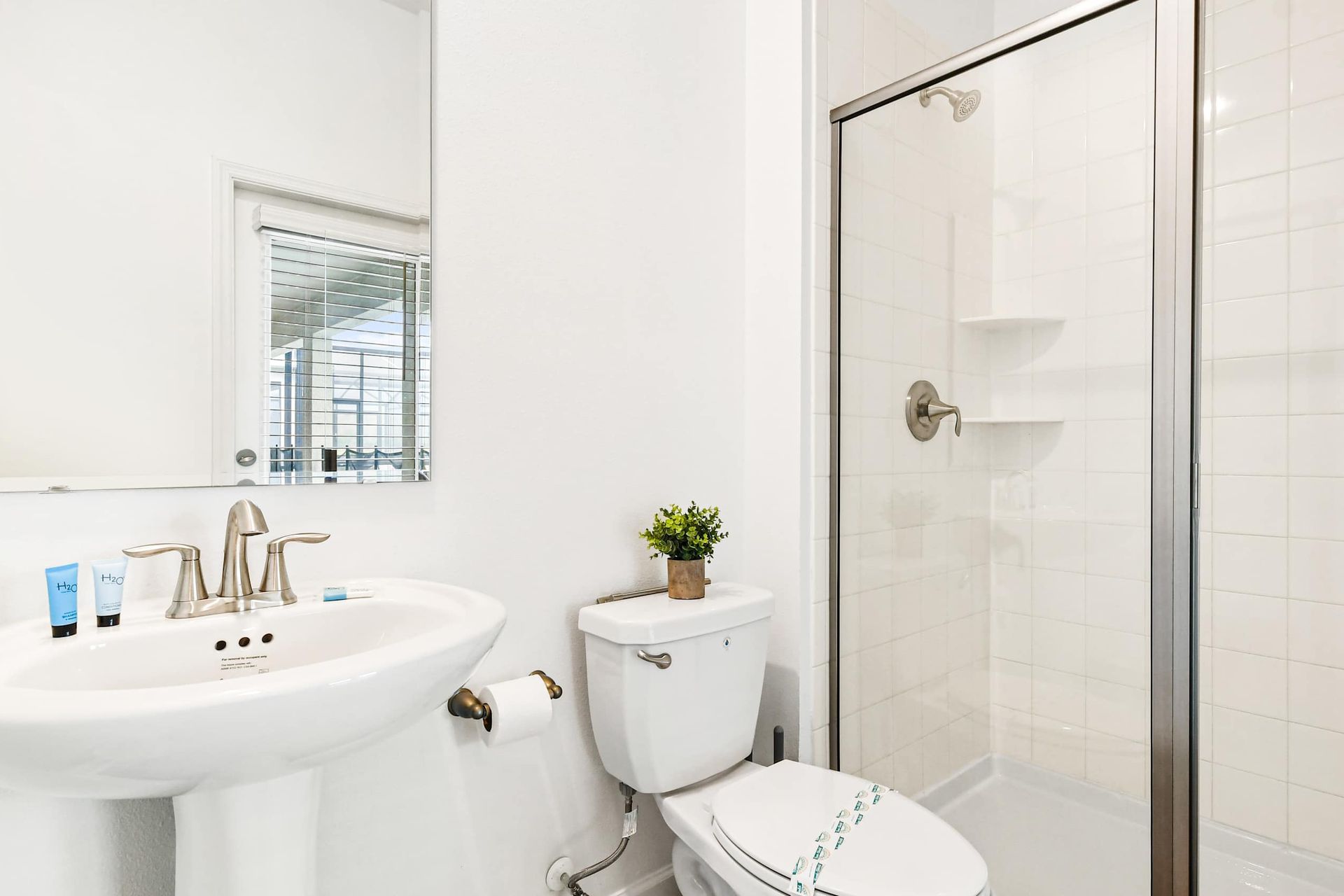 Crisp and clean full bath with walk-in shower, pedestal sink, and poolside access.