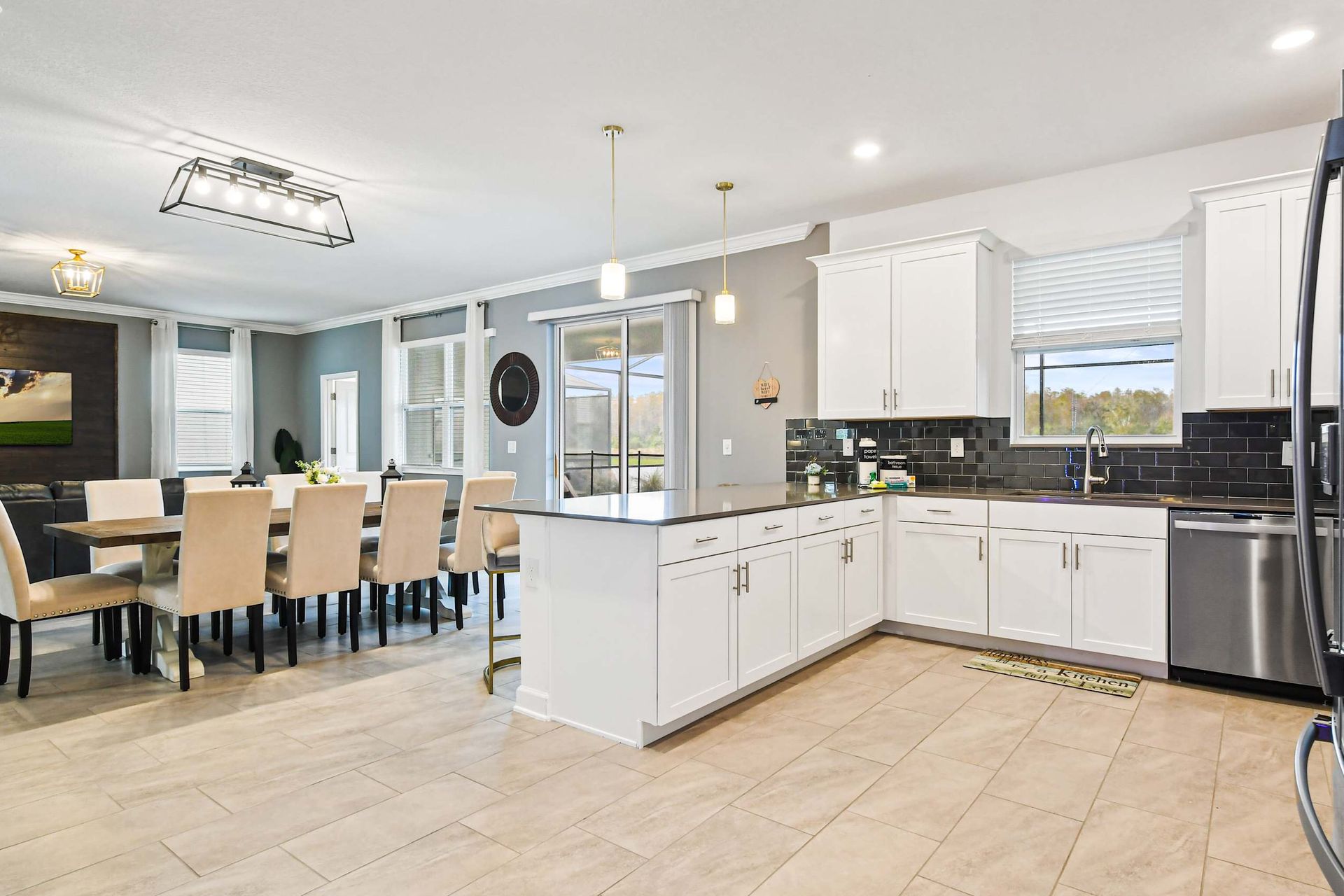 Bright chef’s kitchen with island seating, open dining, and scenic backyard views.