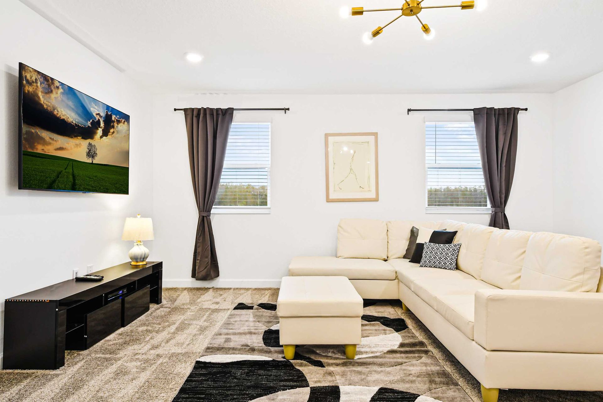 Chic upstairs lounge with plush sectional, smart TV, and warm natural light.