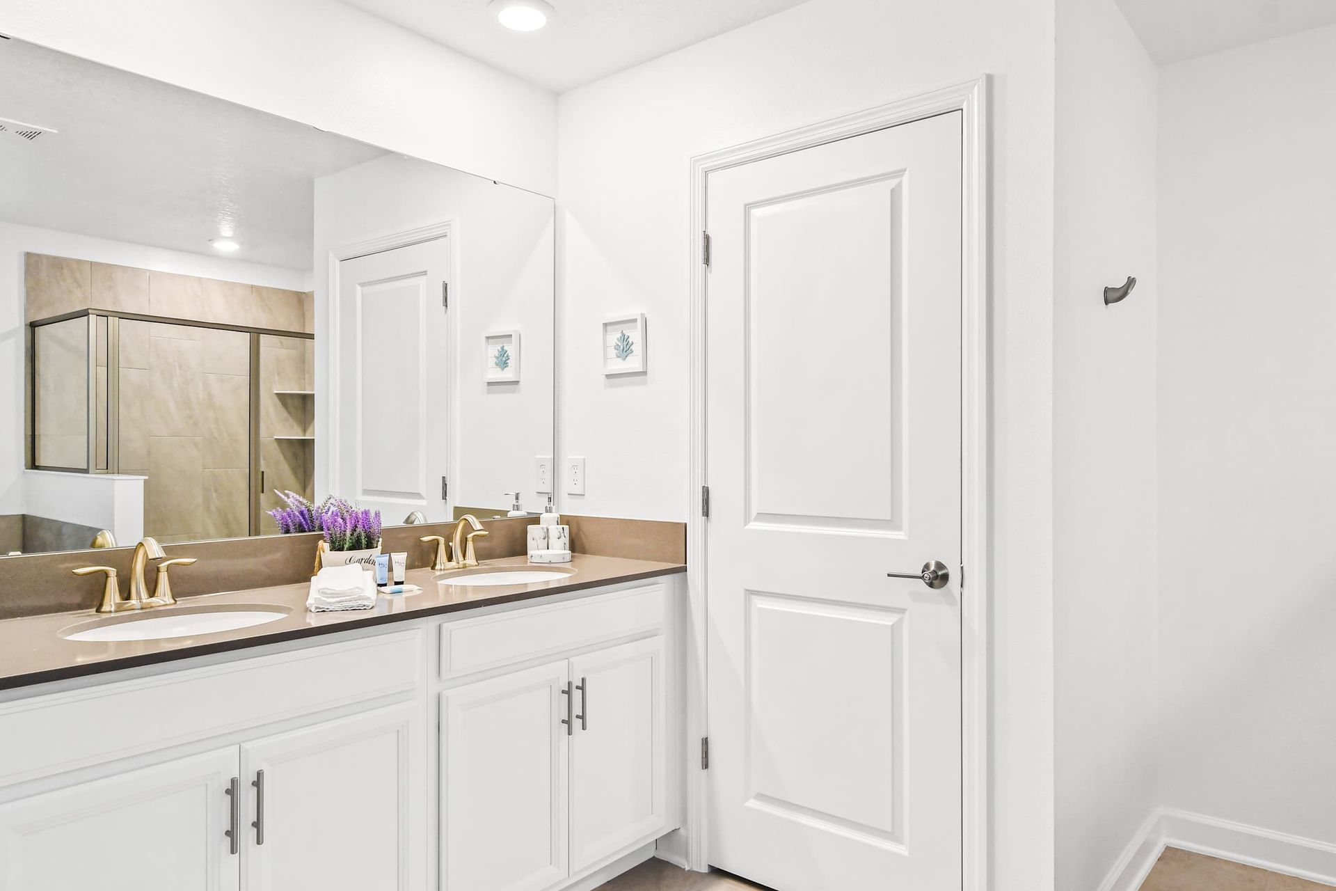 Elegant ensuite bath with double vanity, walk-in shower, and bright coastal décor.