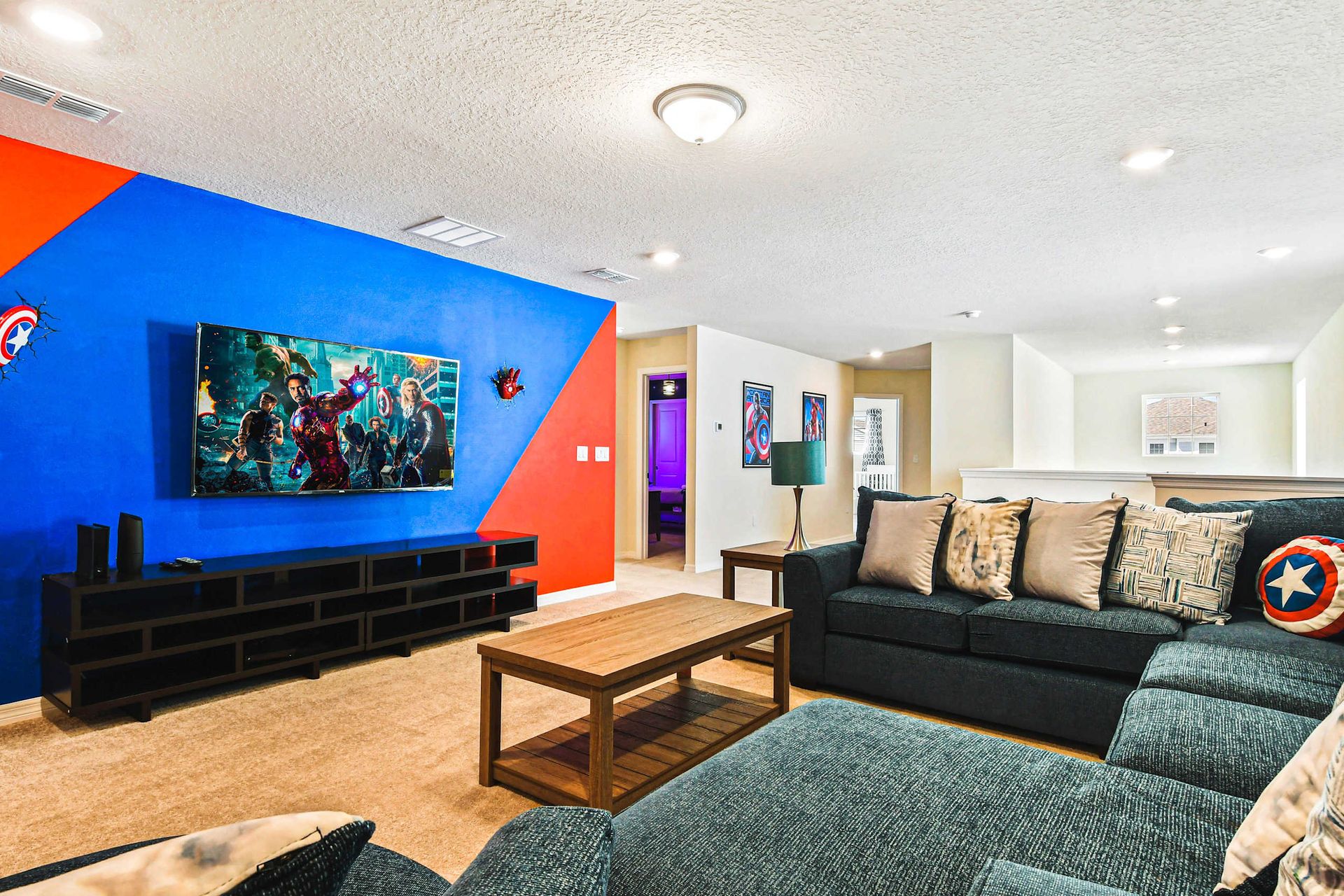 Marvel-themed media room with epic wall art, huge sectional, and big-screen fun