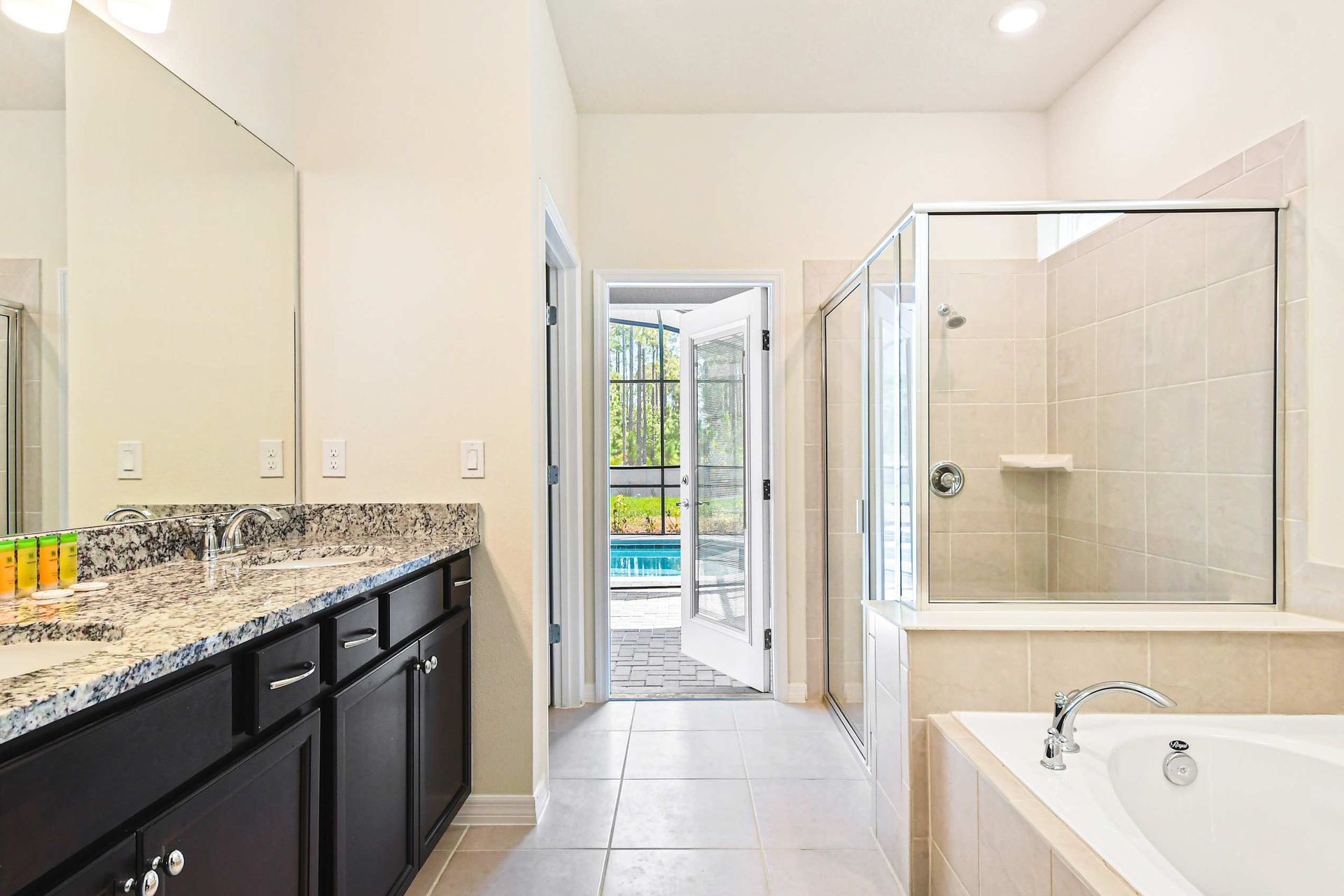 Luxurious ensuite with double vanity, soaking tub, walk-in shower, and pool access