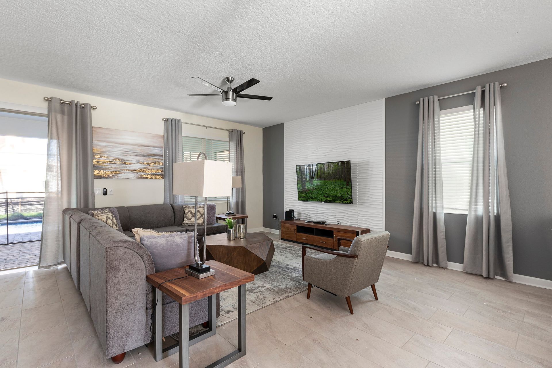 Modern living room with soft grays, cozy seating, and a stylish TV feature wall.
