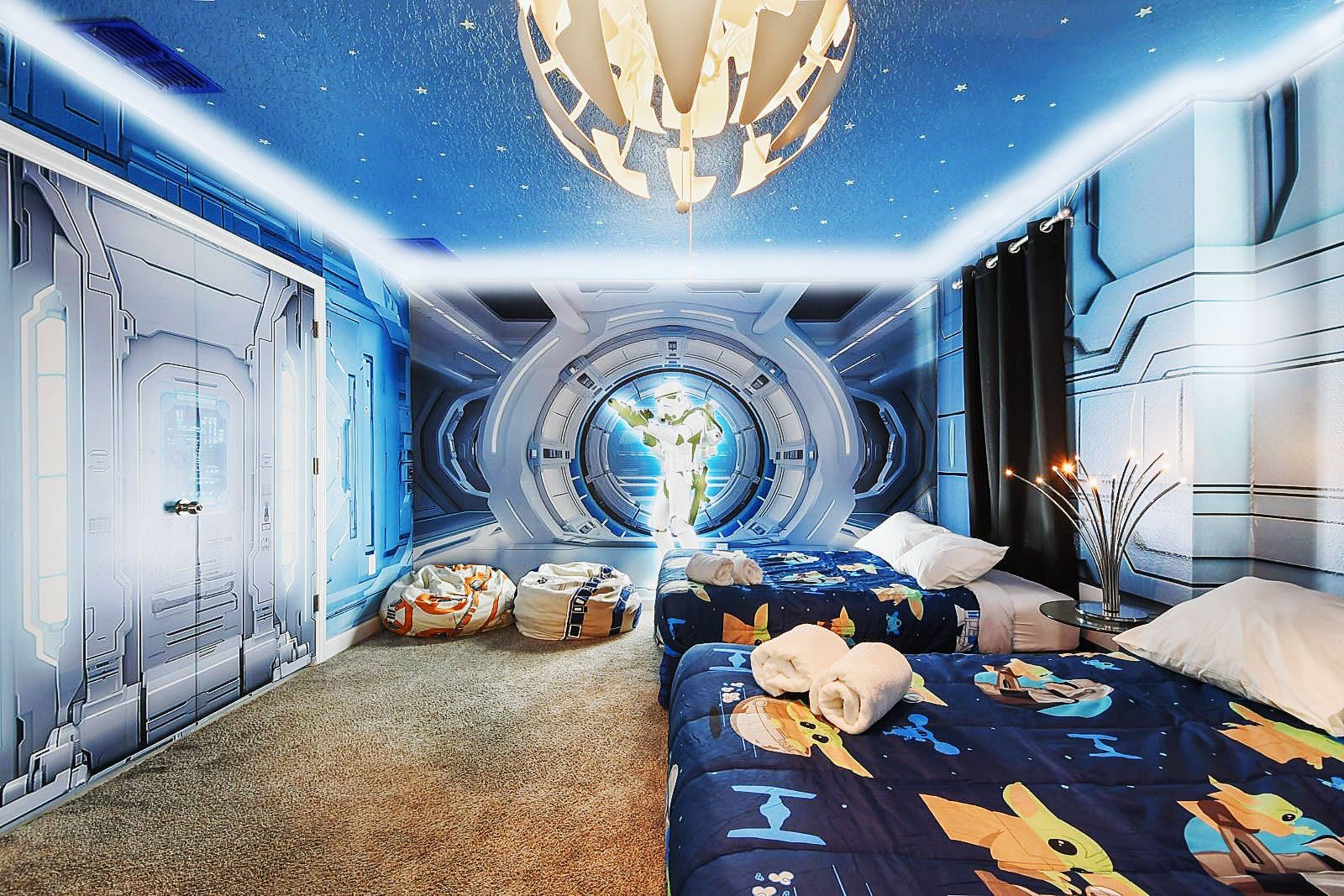 Galactic-themed room with starry decor, cozy beds, and futuristic ambiance.