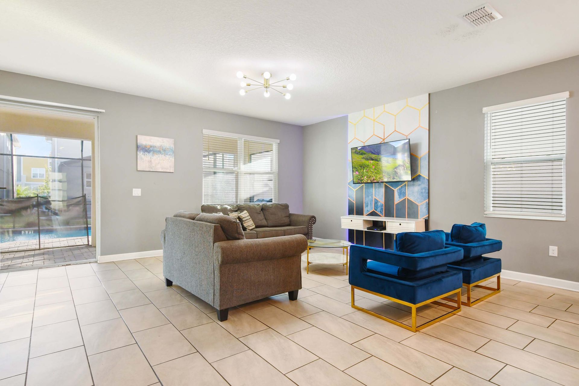 Modern living room w/pool view, stylish seating, and TV wall!