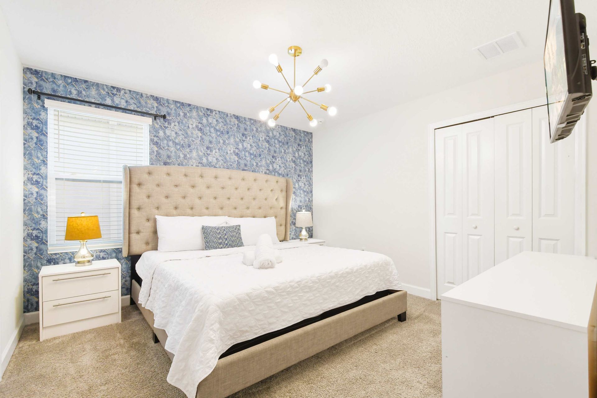 Elegant bedroom with tufted headboard and blue accent wall.