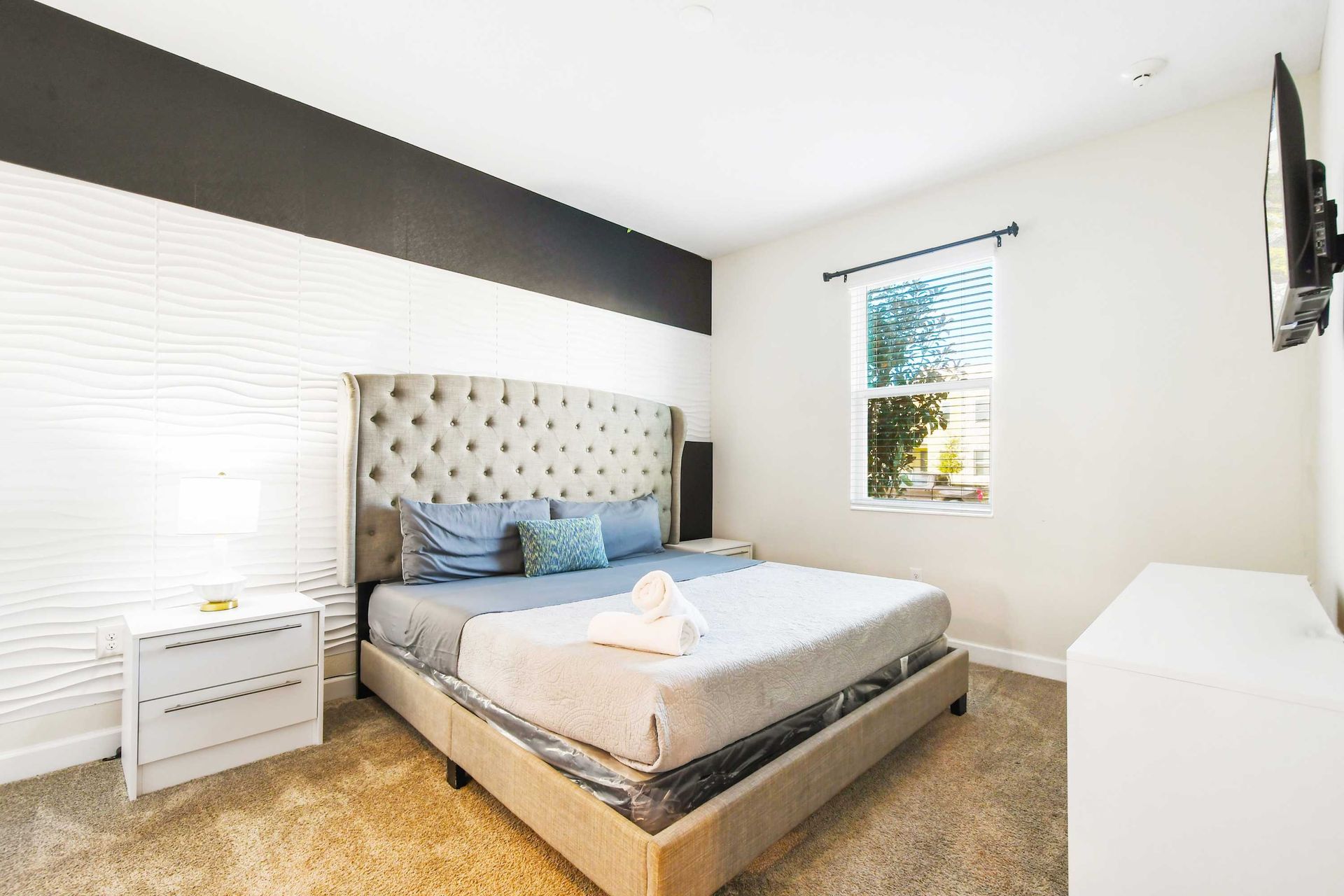 Cozy bedroom with tufted headboard, modern decor, and TV!