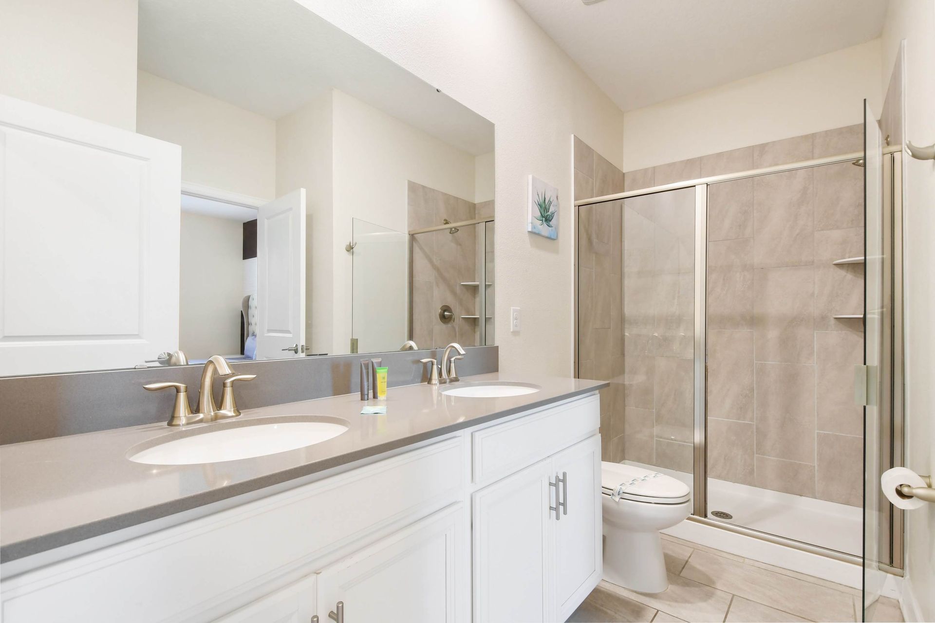 Modern bathroom with dual sinks, sleek countertops, and glass shower.