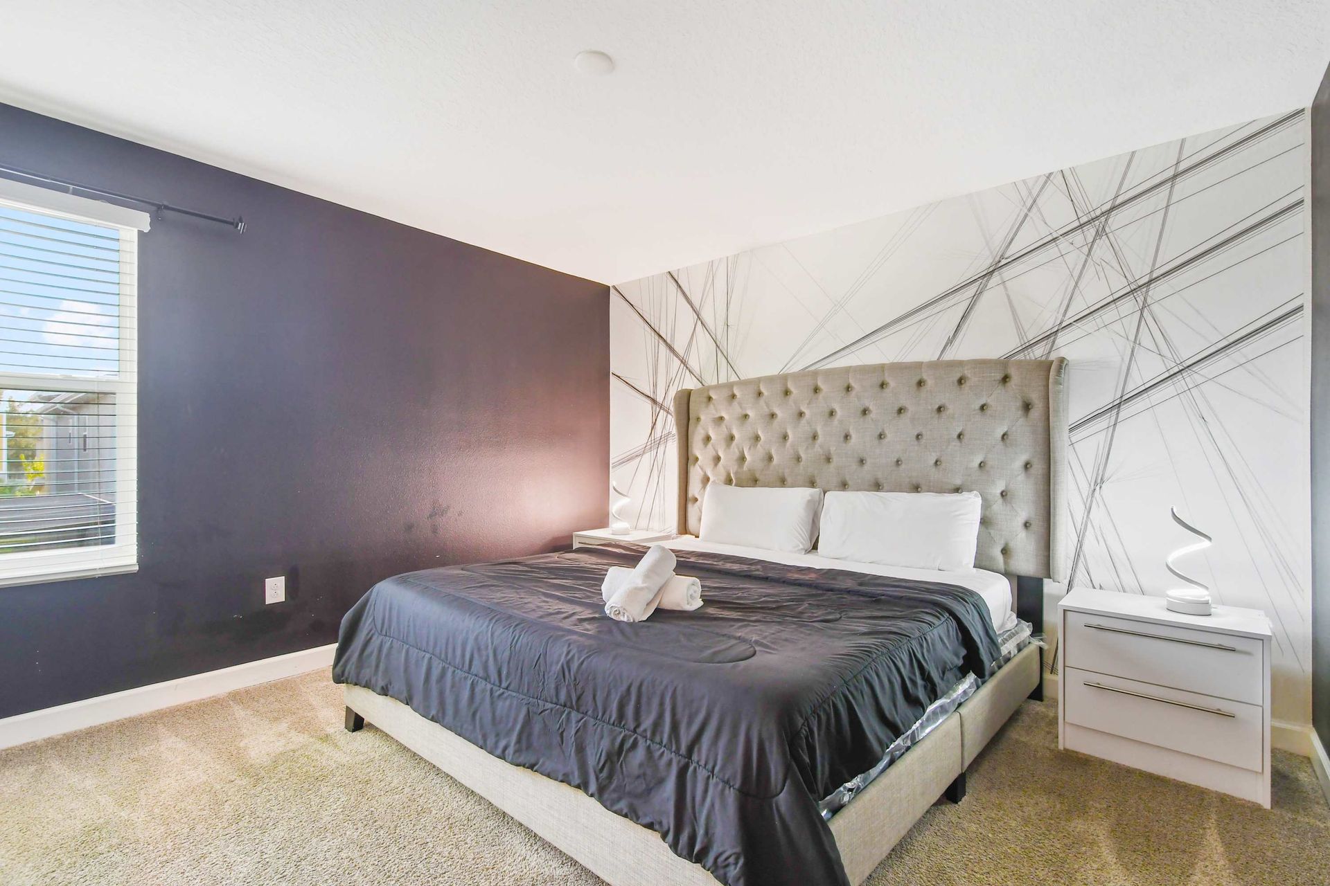 Modern bedroom with abstract feature wall and tufted headboard.