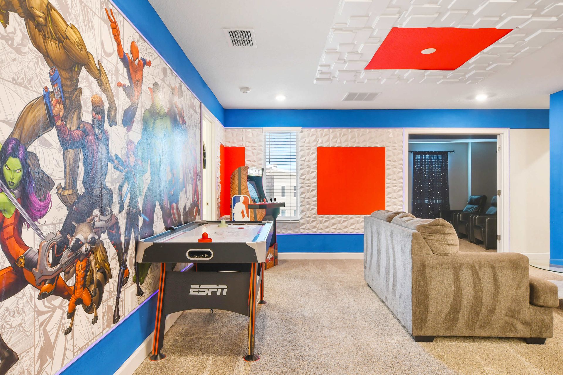 Vibrant game room with superhero wall art, arcade, and air hockey.