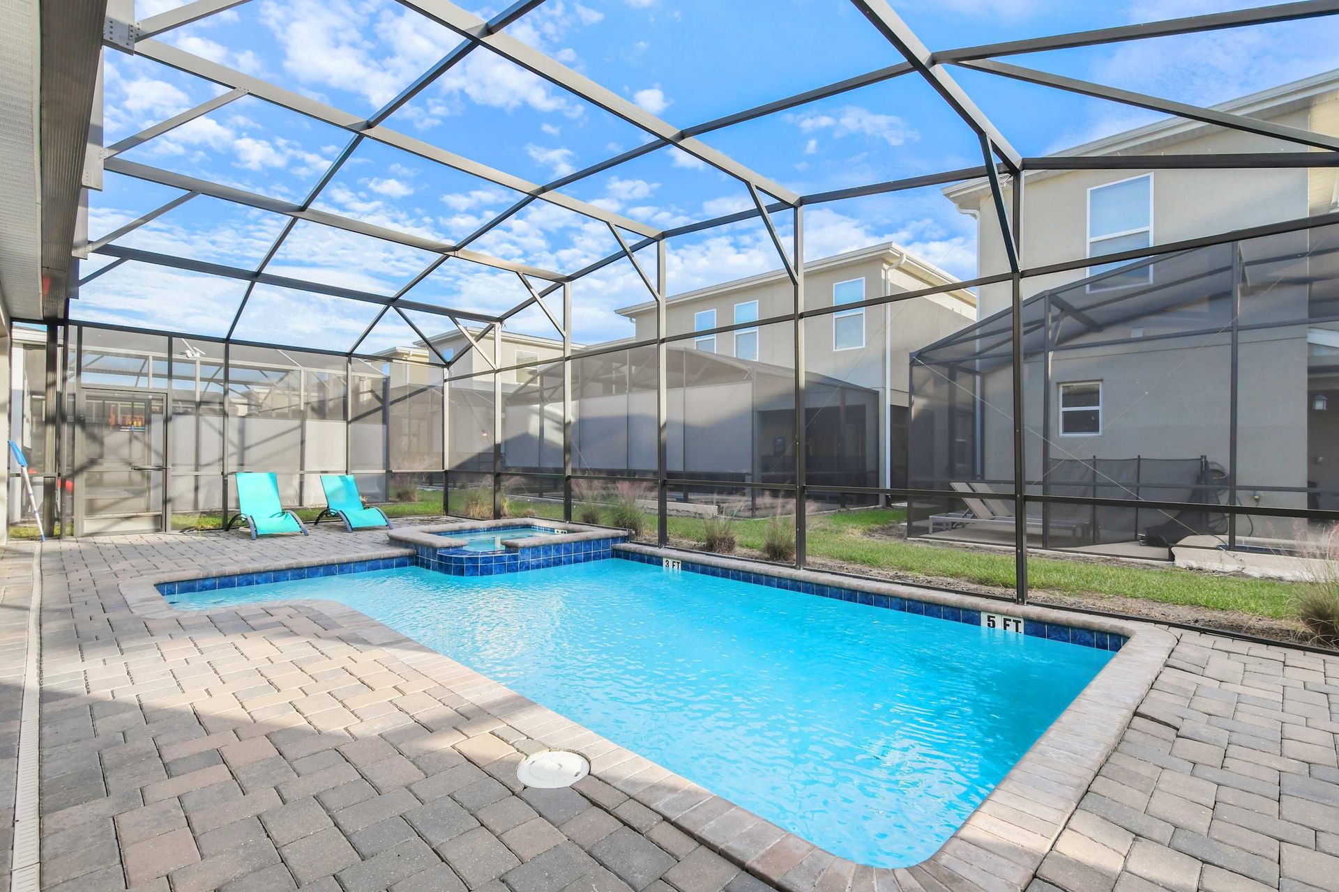 Relaxing screened-in pool area with spa and modern pavers.