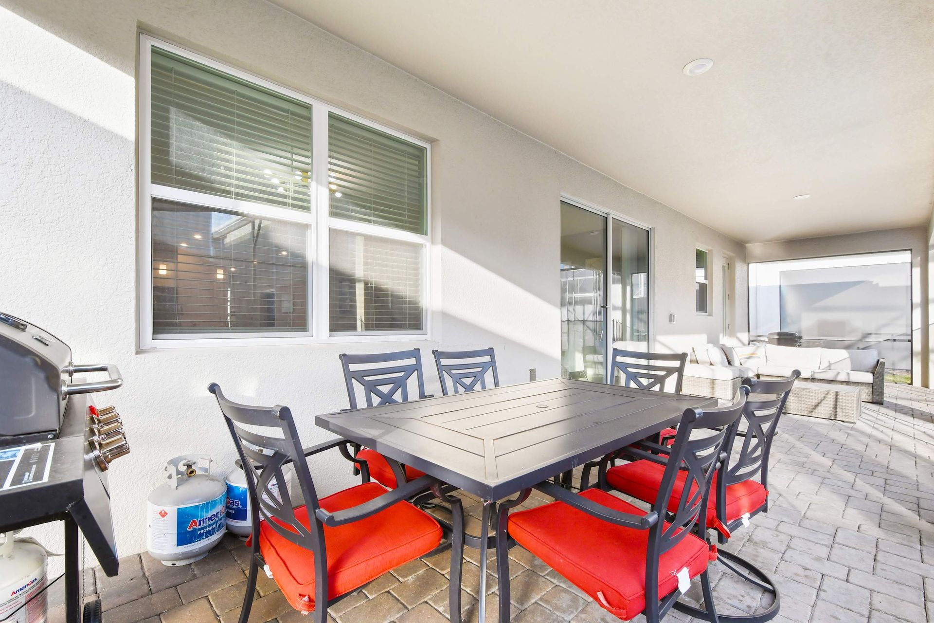 Outdoor dining area with grill and cozy seating under a shaded patio.