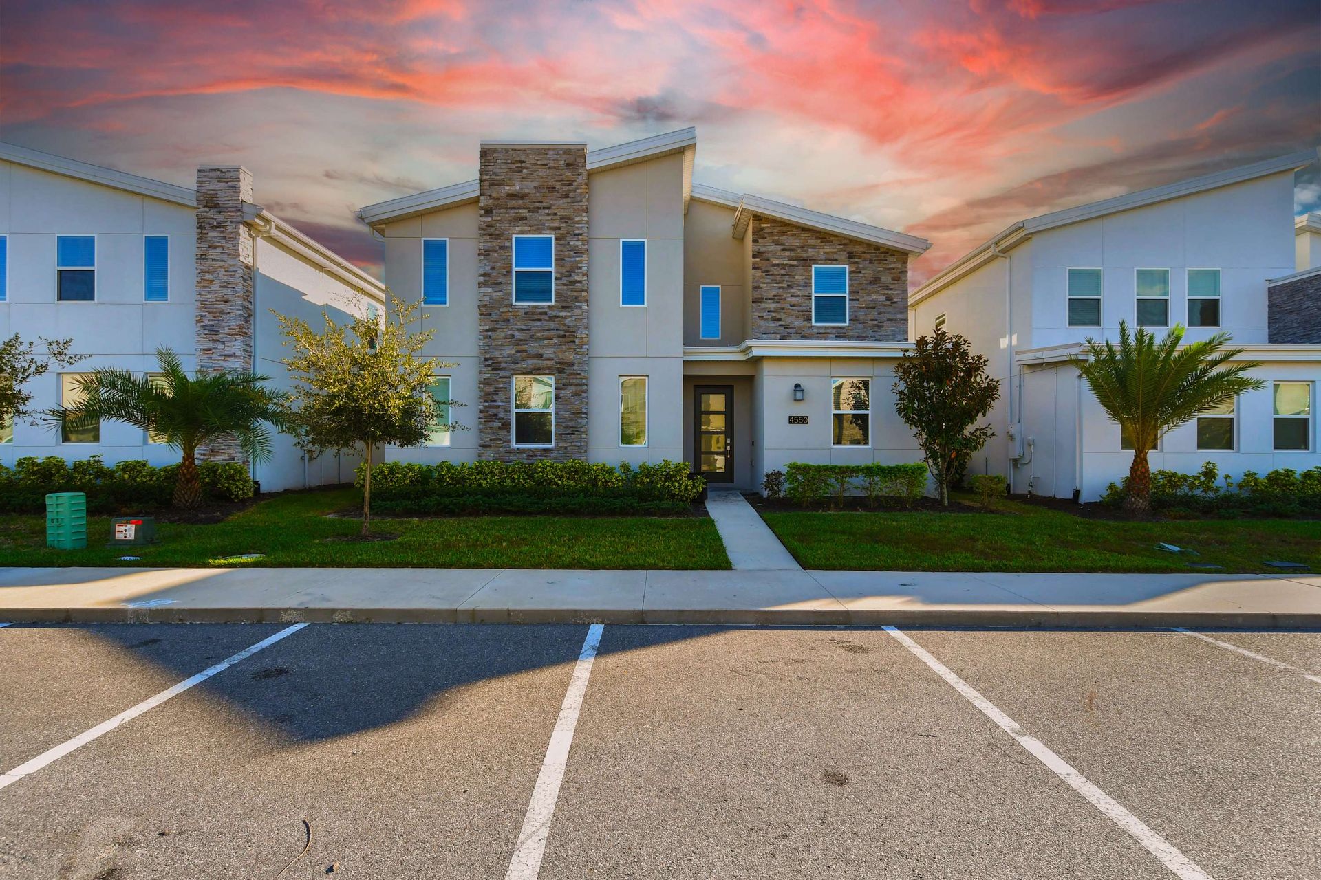 Modern two-story home with a stunning stone facade at sunset.