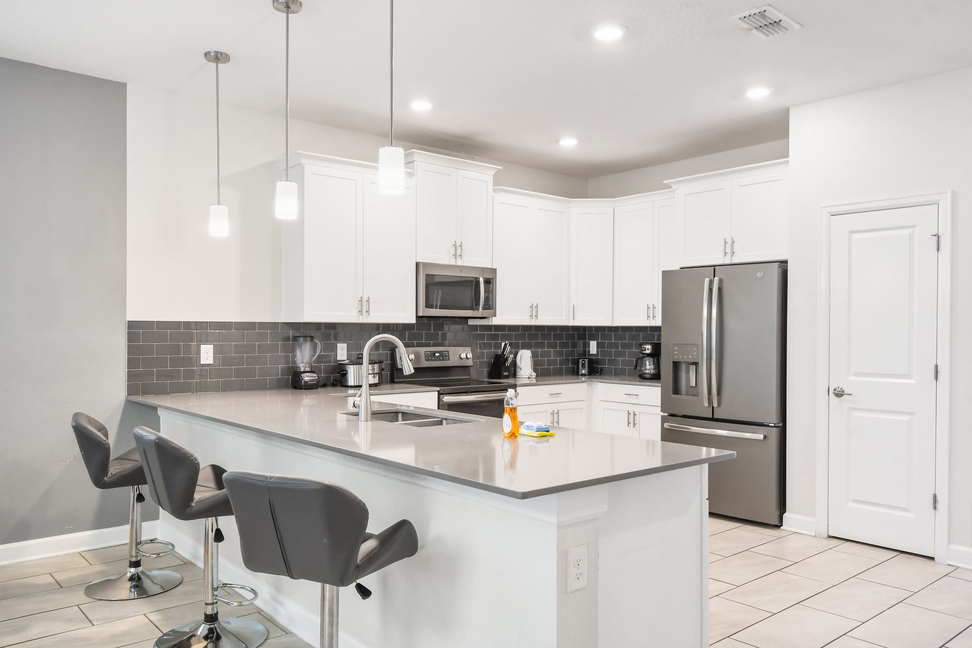 Modern kitchen with white cabinets, gray backsplash, island.