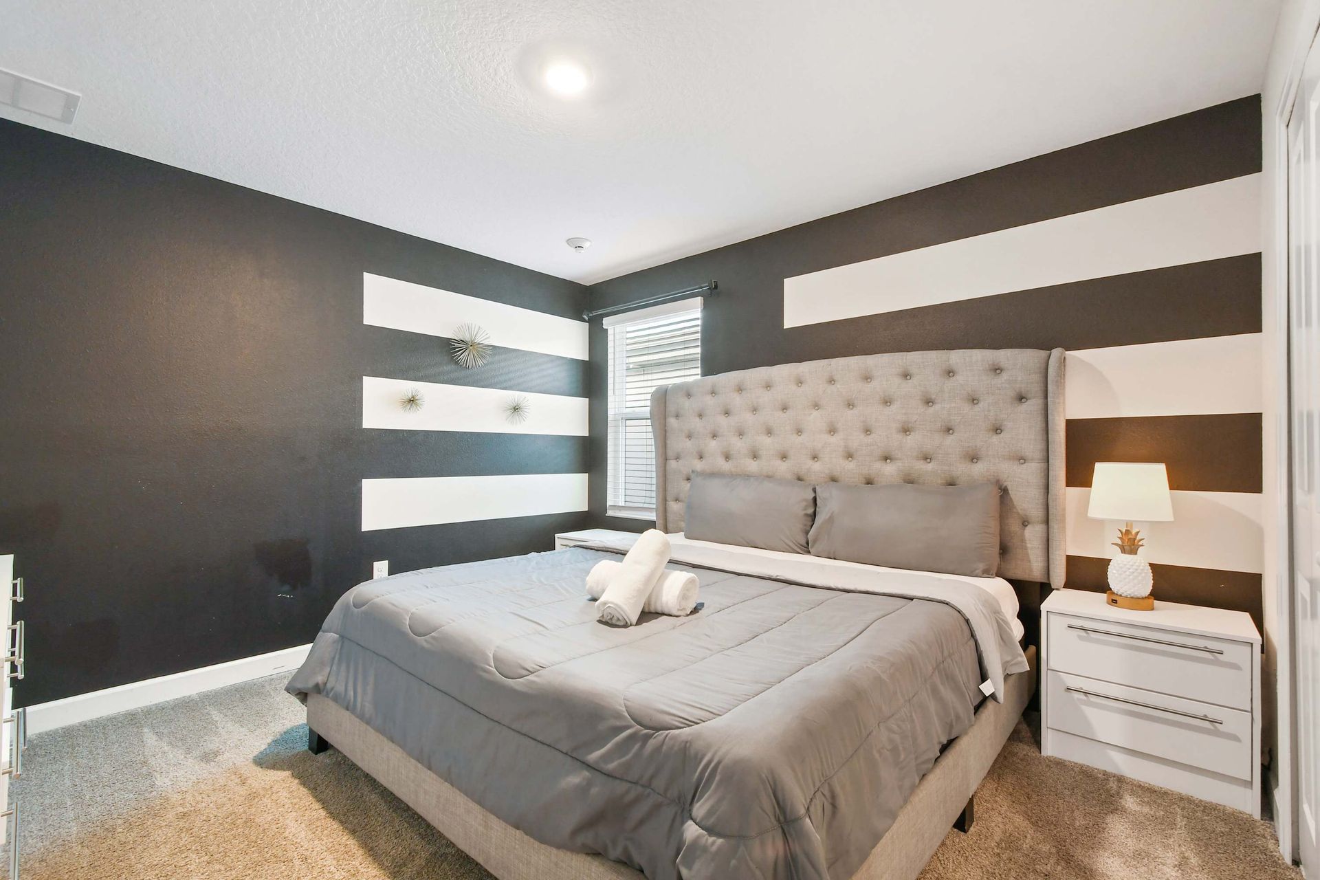 Stylish bedroom with black-and-white striped accent wall.