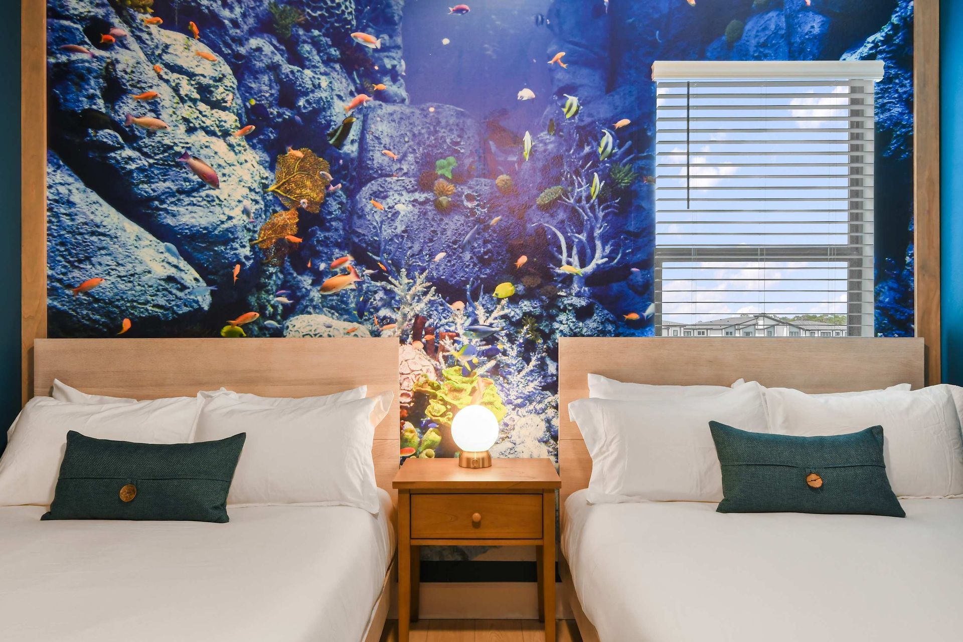 Dive into a vibrant underwater escape with twin beds and a coral reef mural.