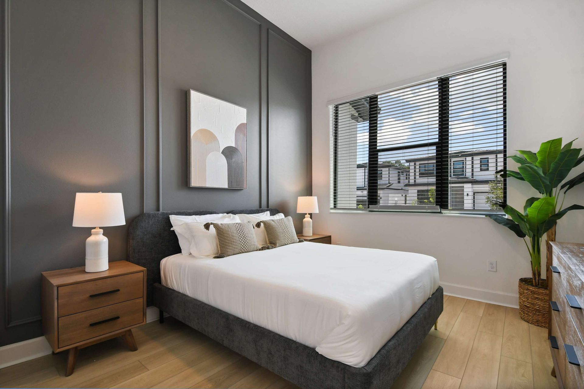 Chic queen suite with moody accent wall, natural light, and stylish modern touches.