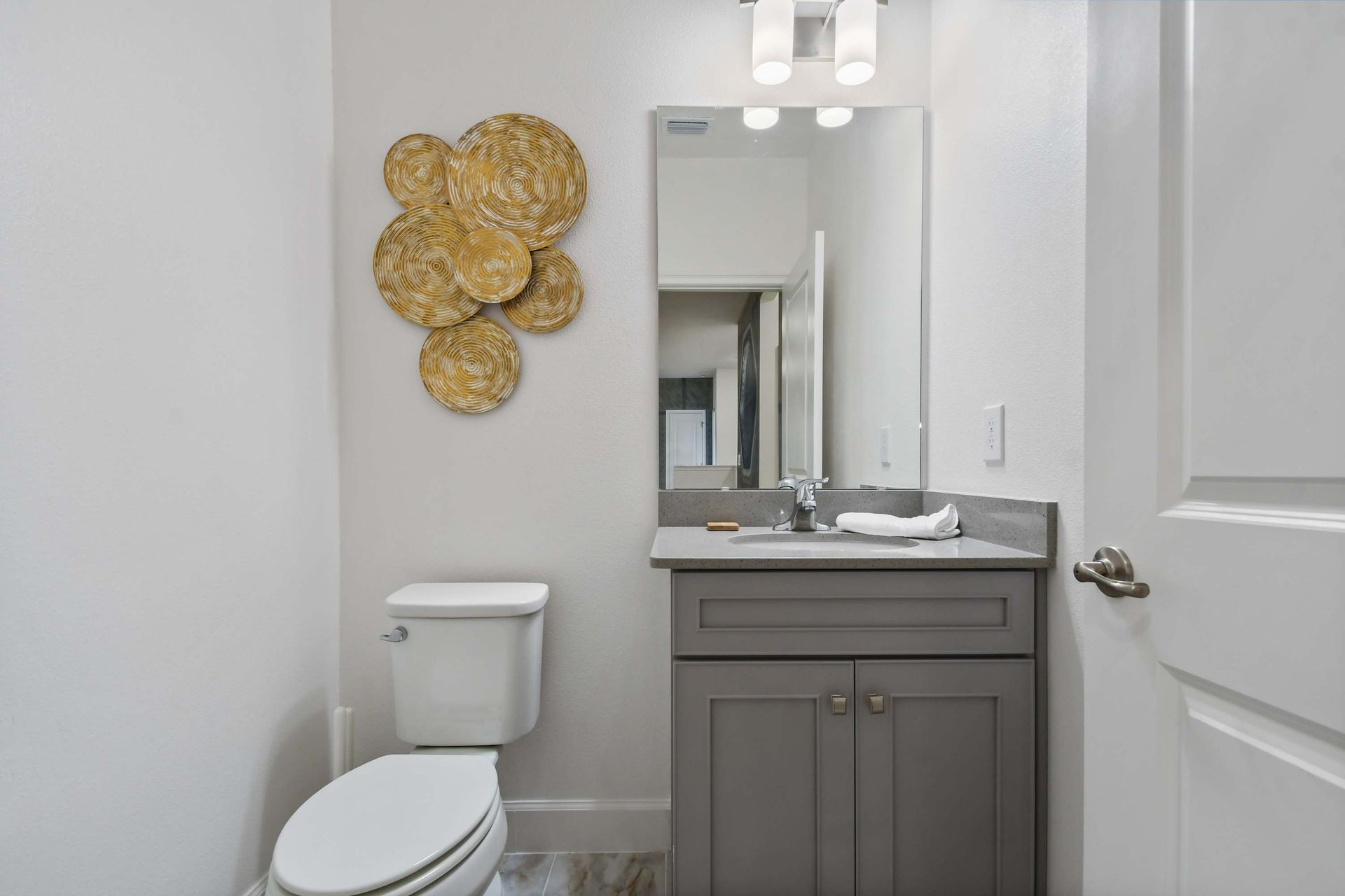 Stylish half bath with sleek vanity, modern lighting, and artistic wall decor.