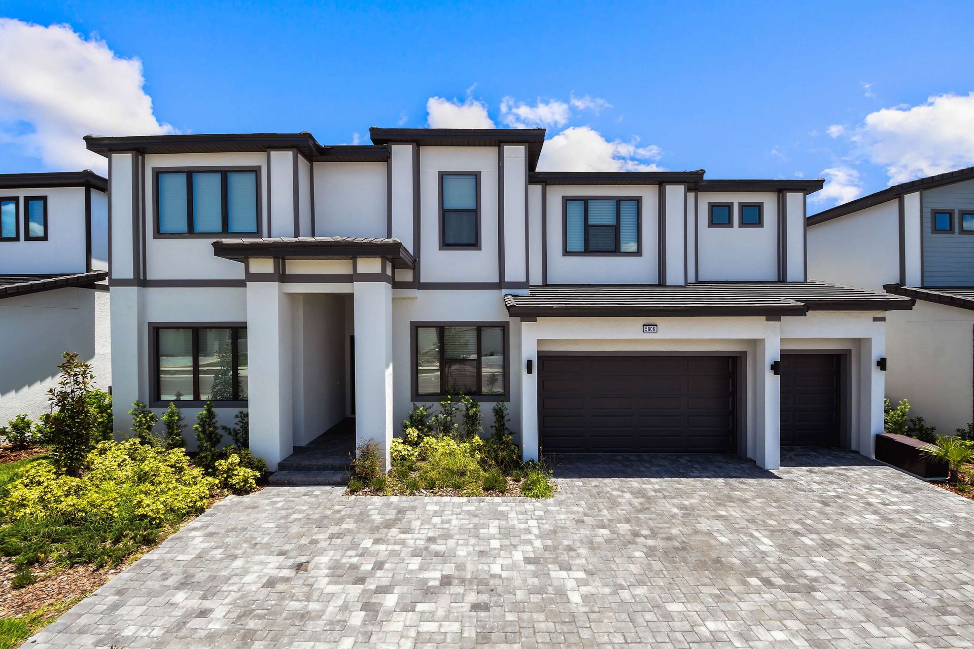Modern two-story villa with spacious driveway, sleek design, and stylish curb appeal.
