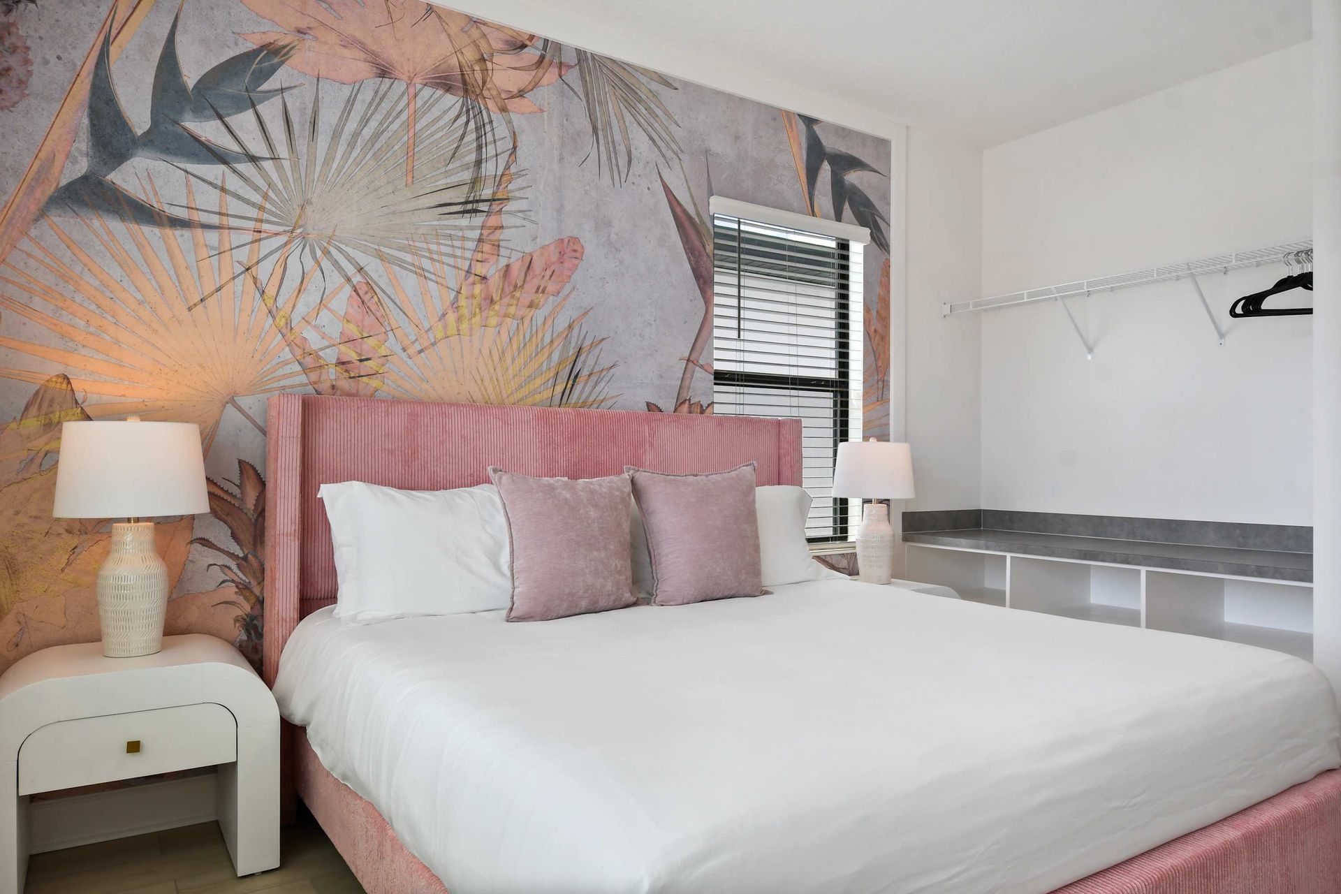 Tropical accent wall and blush-toned king bed create a dreamy, serene escape.