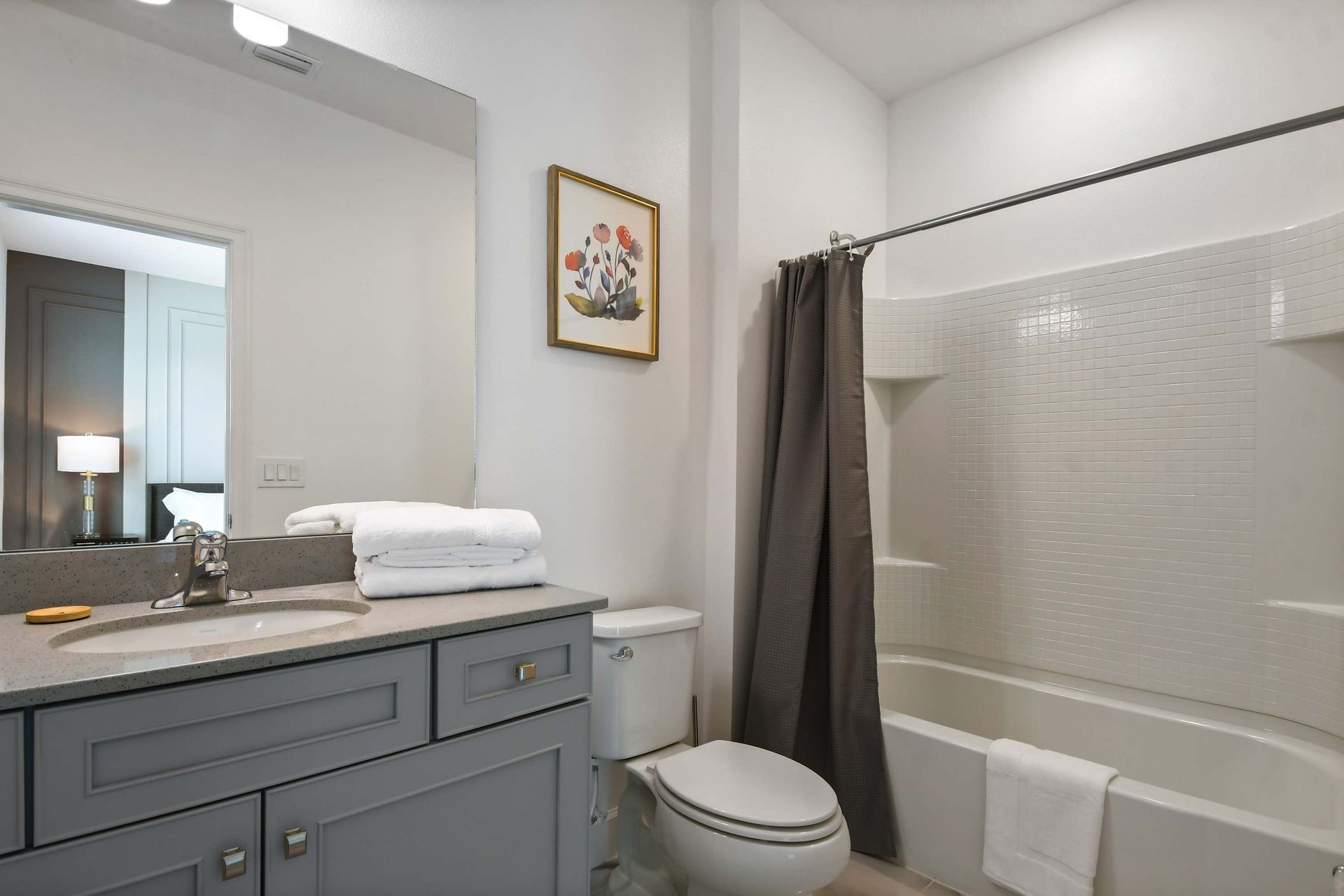 Bright and airy bathroom with large mirror, modern vanity, and full shower-tub combo.