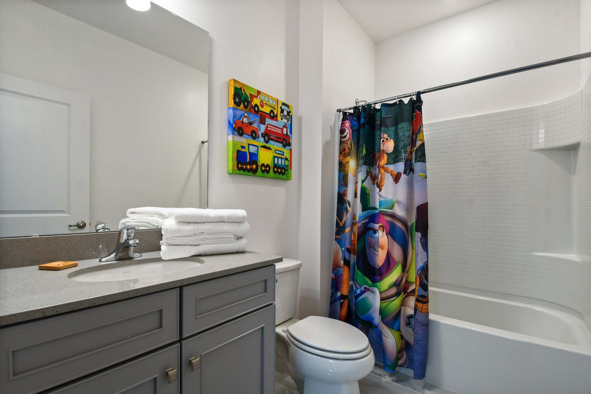 Playful Toy Story-themed bathroom with colorful decor and a full tub-shower combo.