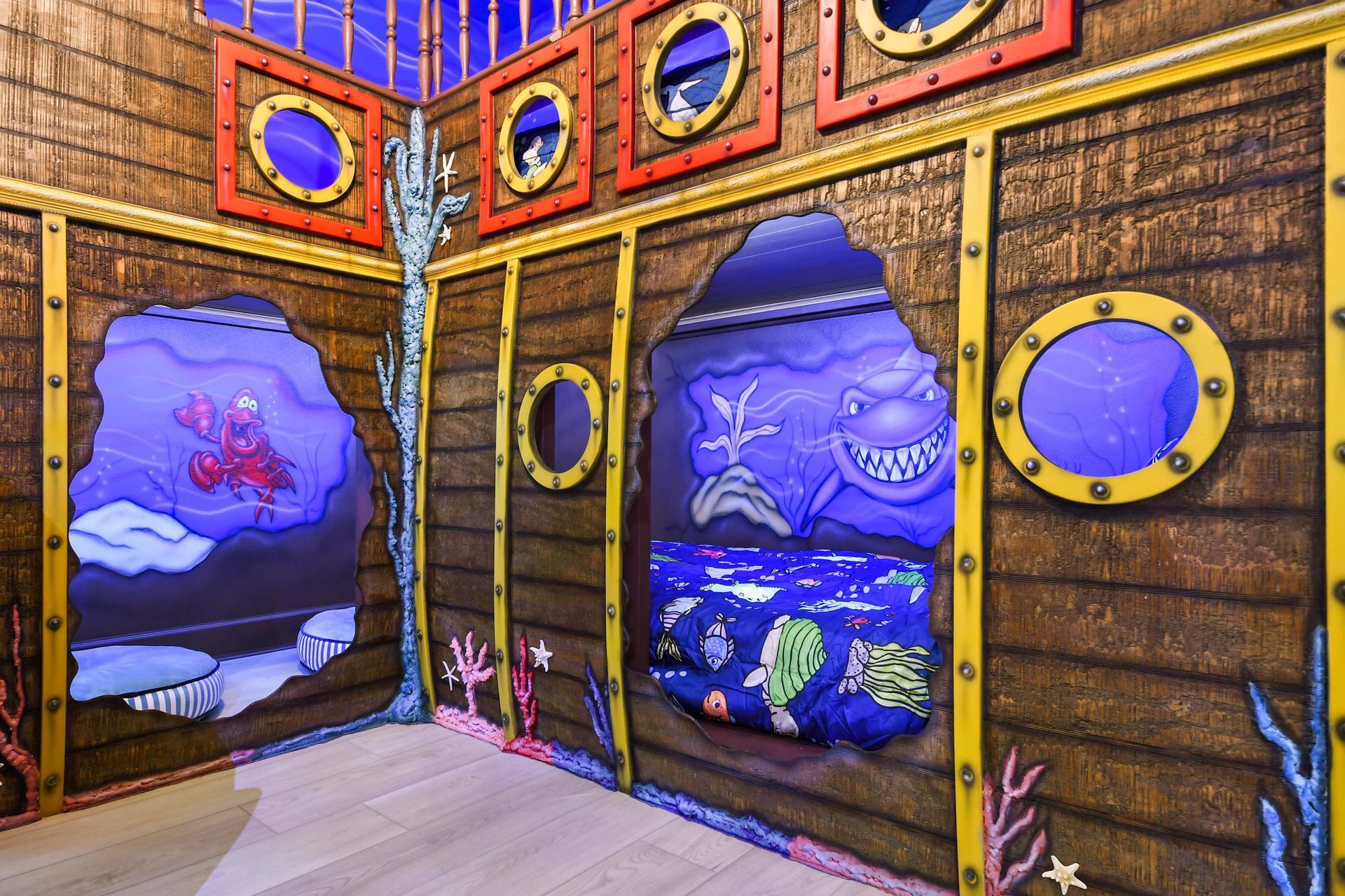 Underwater-themed kids’ room designed like a pirate ship, with vibrant aquatic murals and cozy built-in bunks.