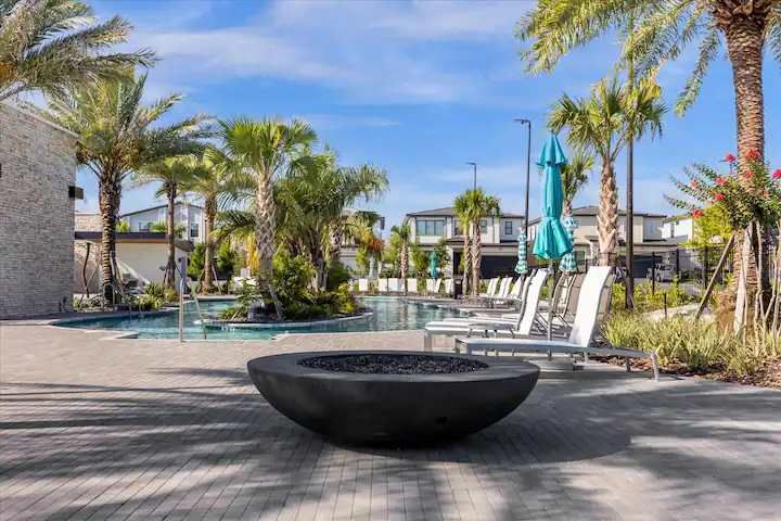 Chic poolside fire pit surrounded by loungers, palms, and resort tranquility.
