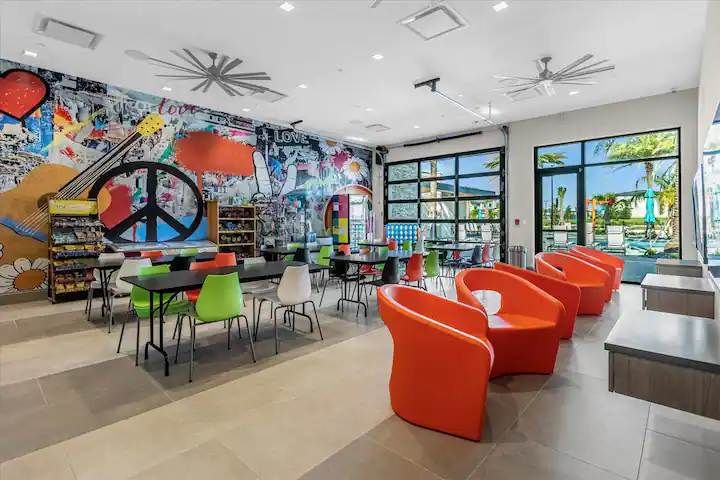 Vibrant game lounge with colorful seating, peace-themed murals, and pool access.
