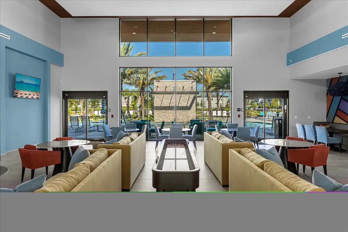 Elegant clubhouse lounge with shuffleboard, stylish seating, and poolside views.
