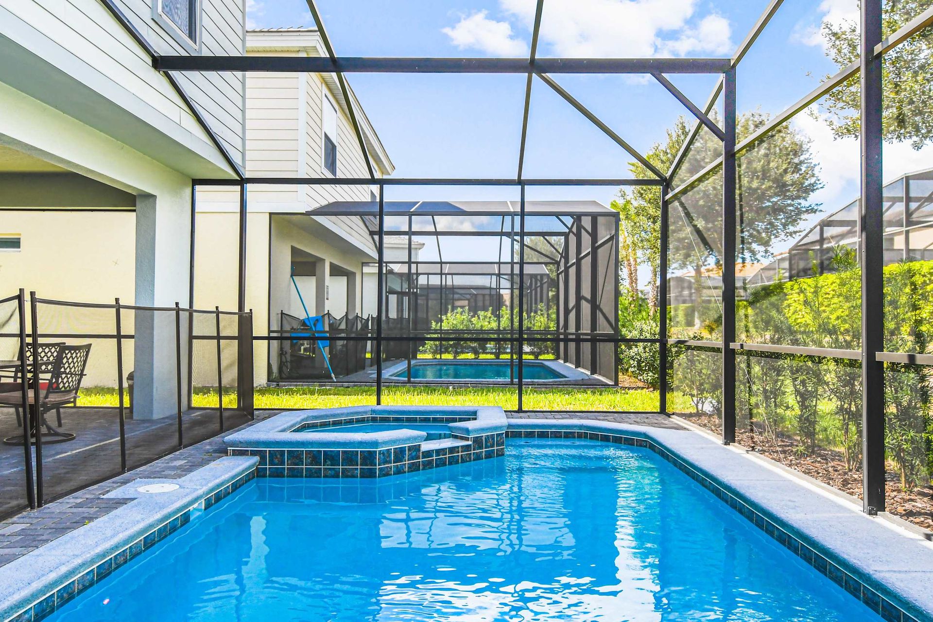 Luxurious poolside retreat! Unwind in style with this inviting spa and pool, framed by lush greenery and a screened patio.