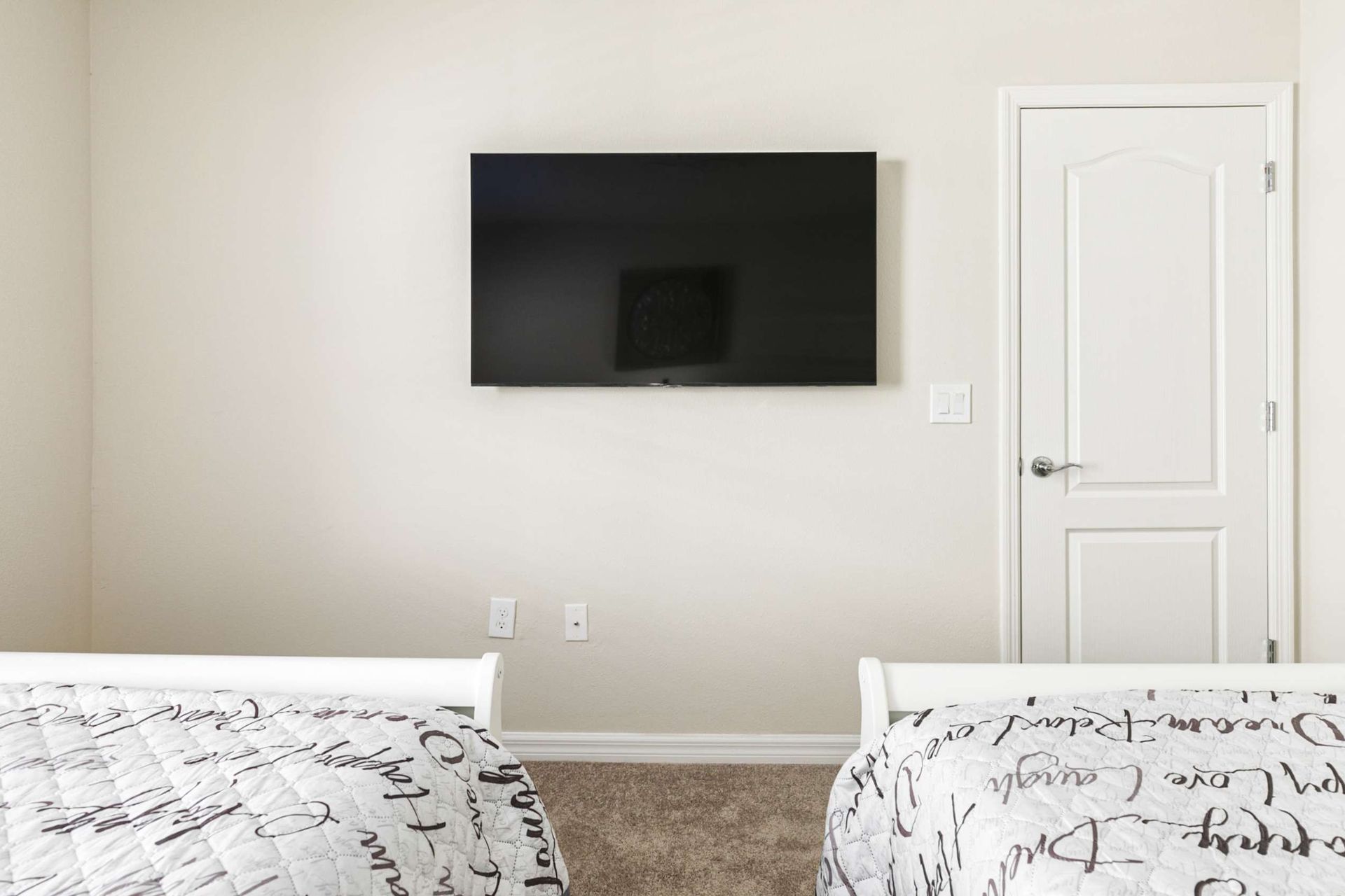 Serene minimalist bedroom featuring sleek wall-mounted tech and plush, scripted linens.