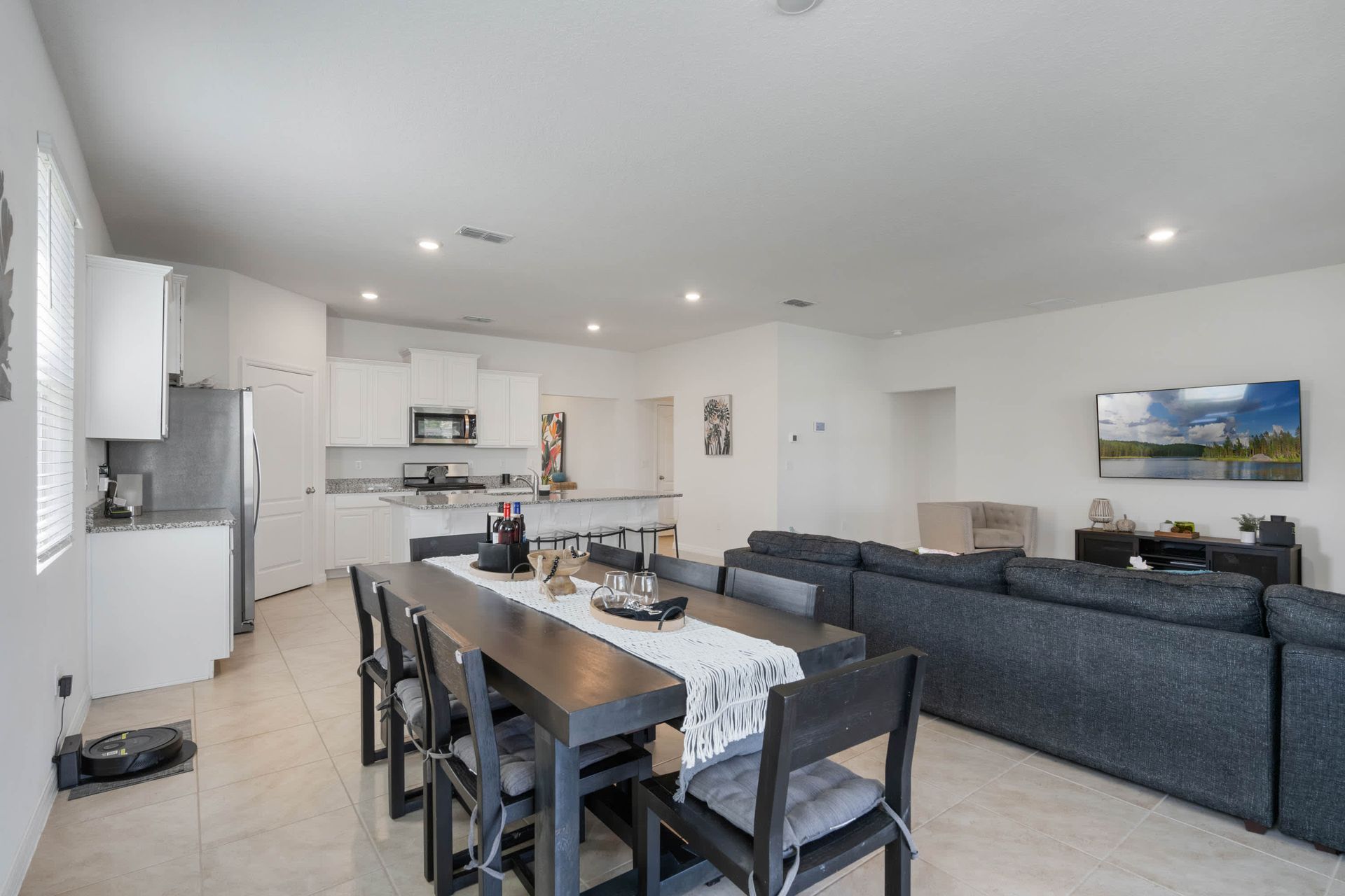 Modern open layout with full kitchen, large dining table, and cozy living area.