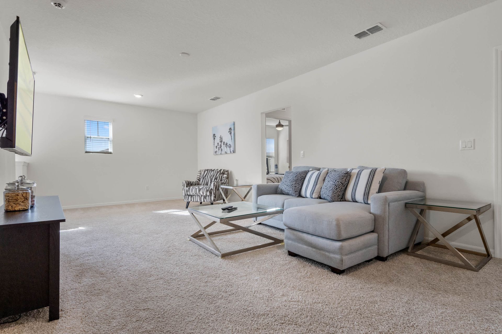 Spacious upstairs loft with plush carpet, comfy seating, and a large smart TV.