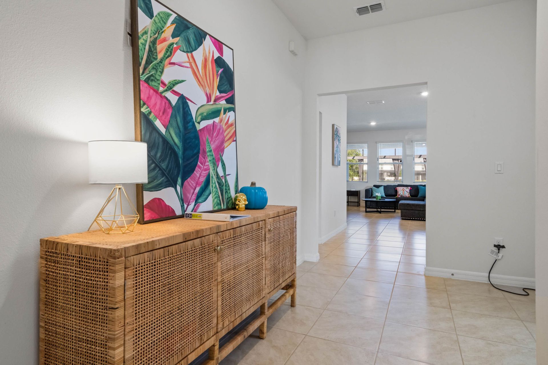 Tropical-themed entryway with bold artwork, rattan console, and warm, welcoming vibes.