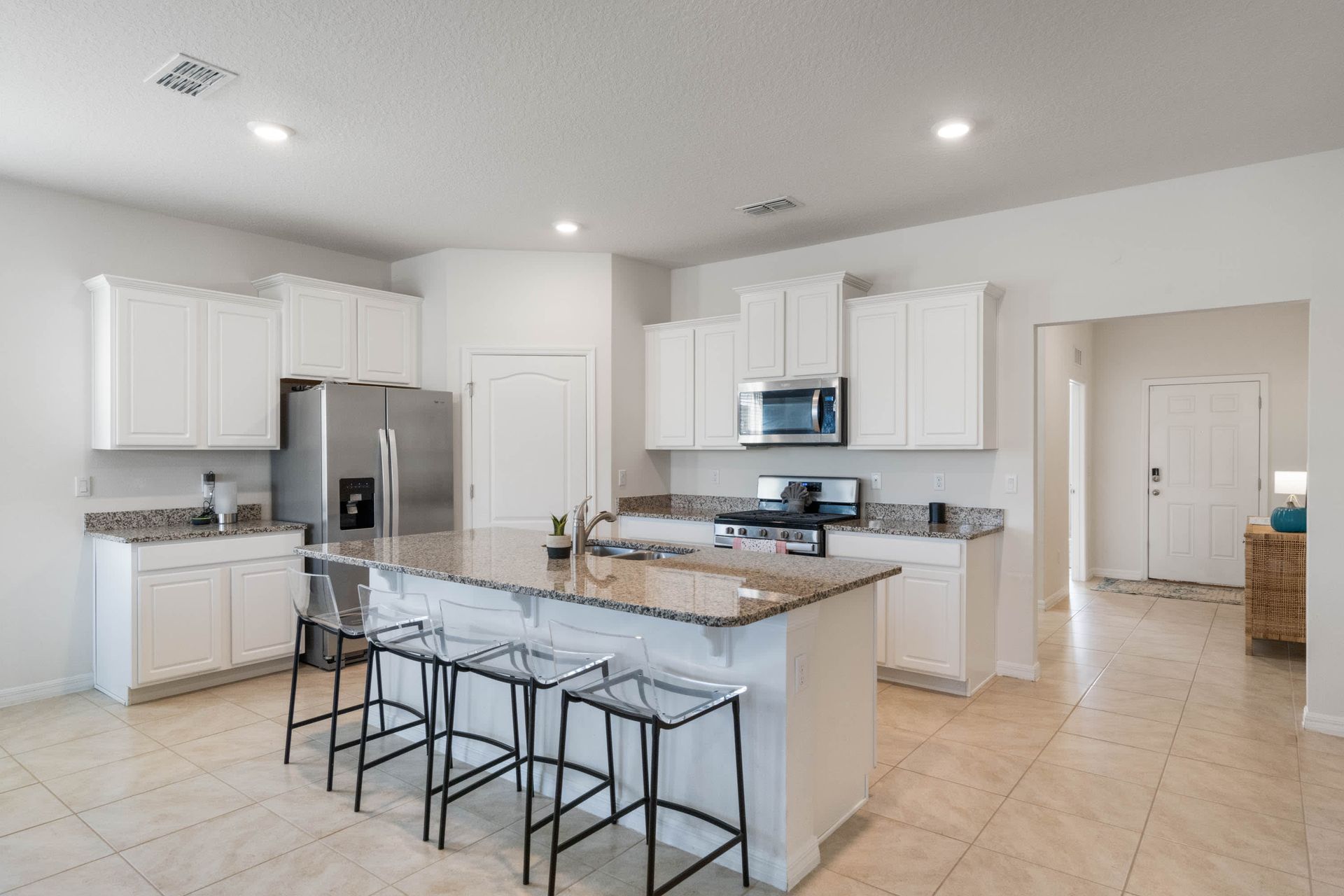 Modern kitchen with granite countertops, stainless steel appliances, and seating for four.