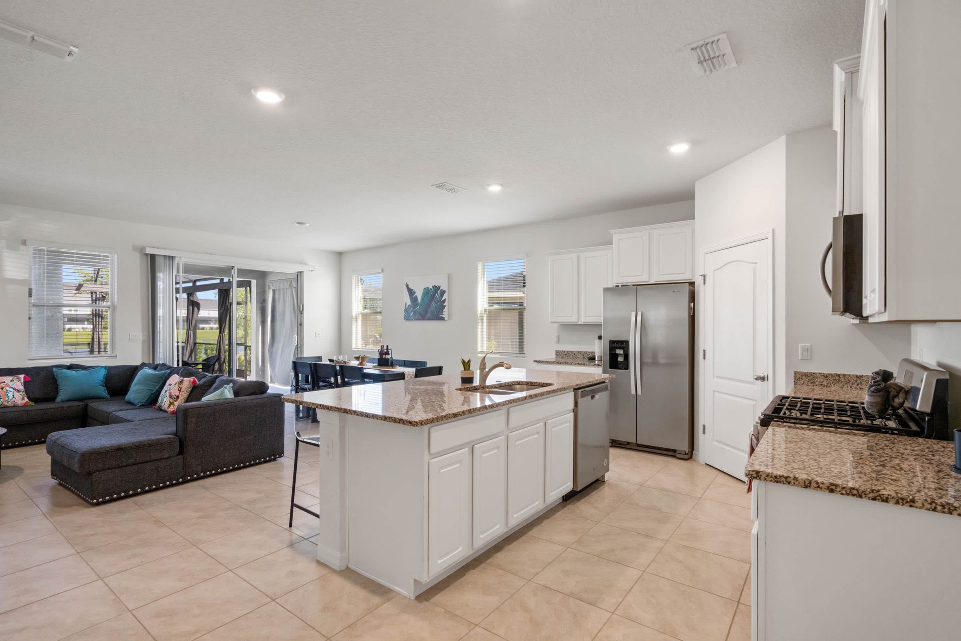 Fully equipped kitchen with granite island, stainless steel appliances, and open layout.