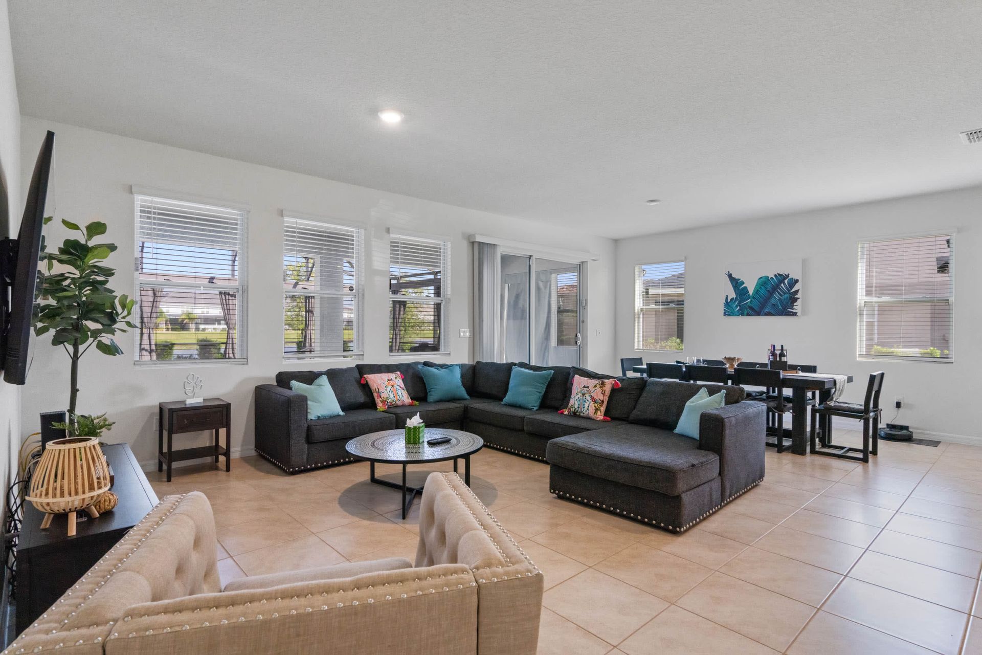 Bright and airy living space with huge sectional, dining table, and pool access.