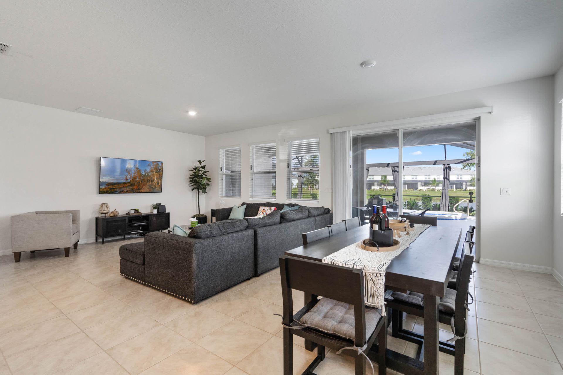 Open-concept living and dining with cozy seating, smart TV, and poolside views.