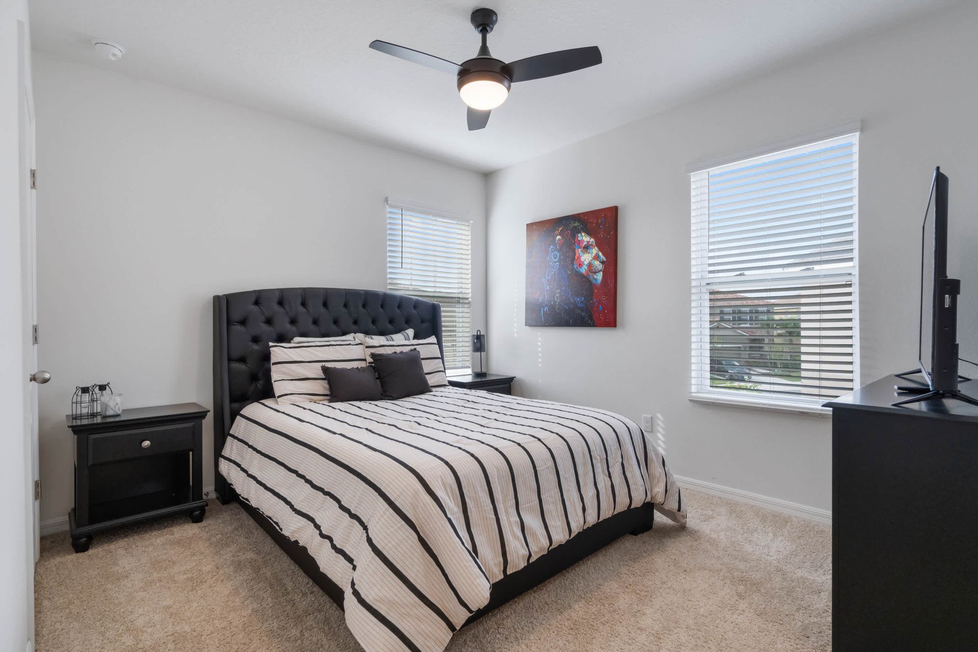 Chic bedroom with queen bed, smart TV, bold wall art, and natural light.