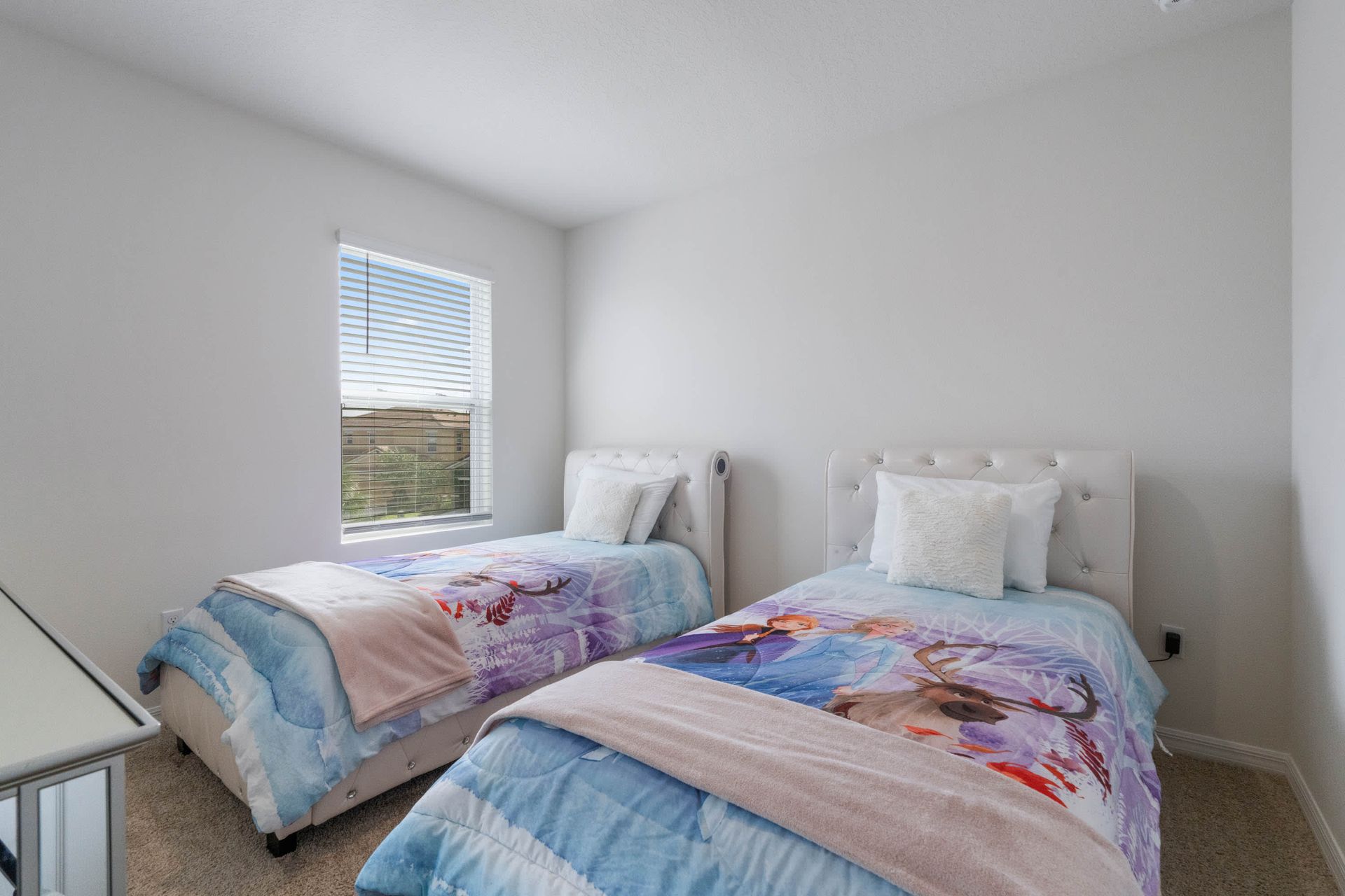 Cozy kids’ room with twin beds, soft carpeting, and cheerful themed bedding.