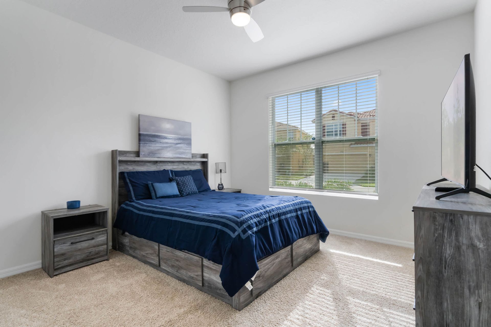 Serene bedroom with rustic wood furnishings, plush carpet, and a large smart TV.