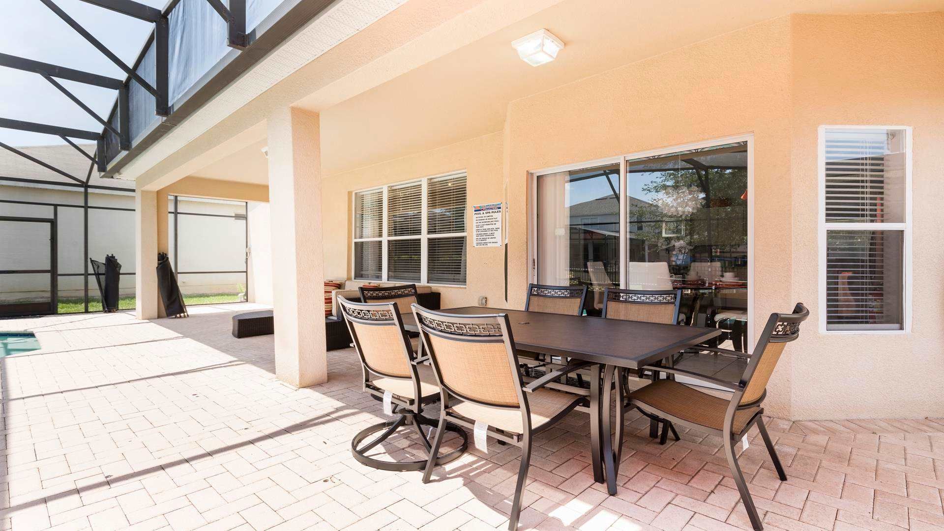 Spacious covered patio with dining area, lounge seating, and screened-in pool.