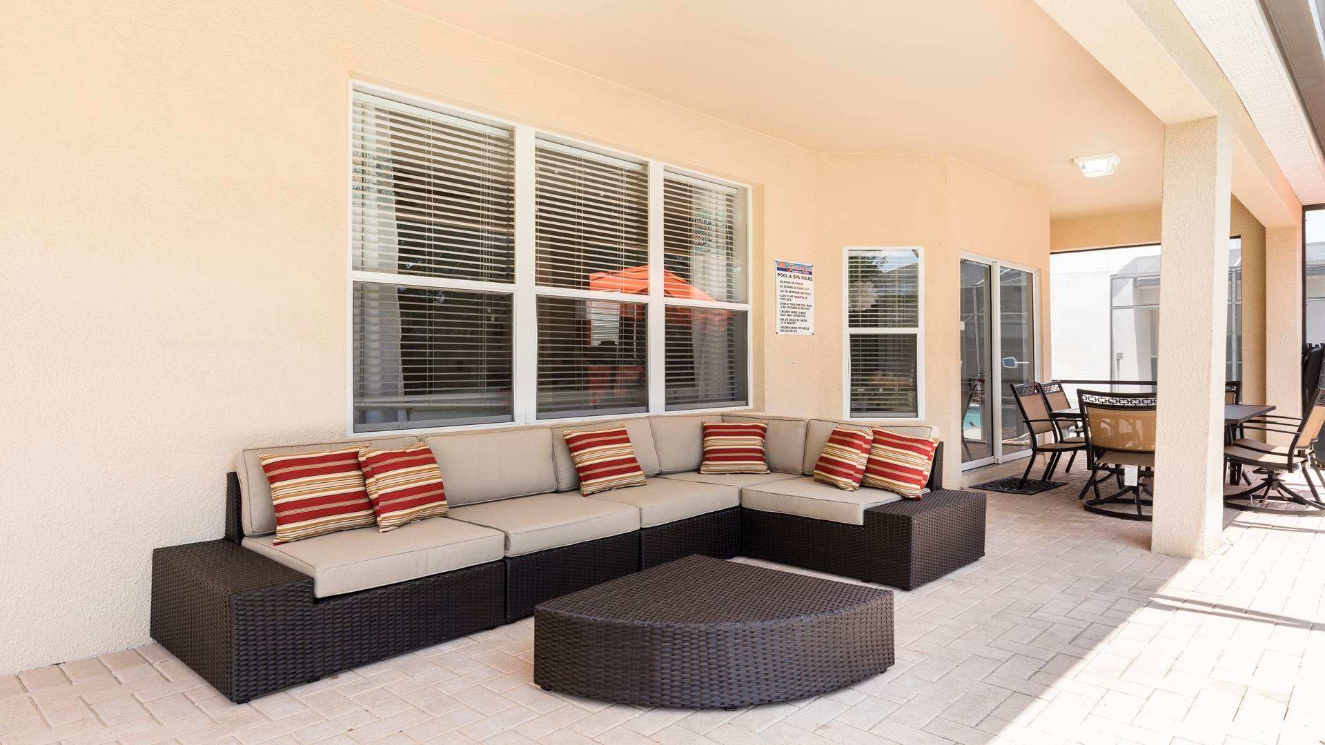 Relax in this spacious covered patio with cozy seating, dining area, and pool access.