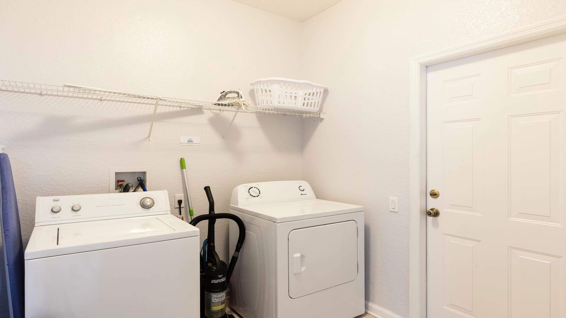 Convenient laundry room with washer, dryer, storage shelf, and cleaning essentials.