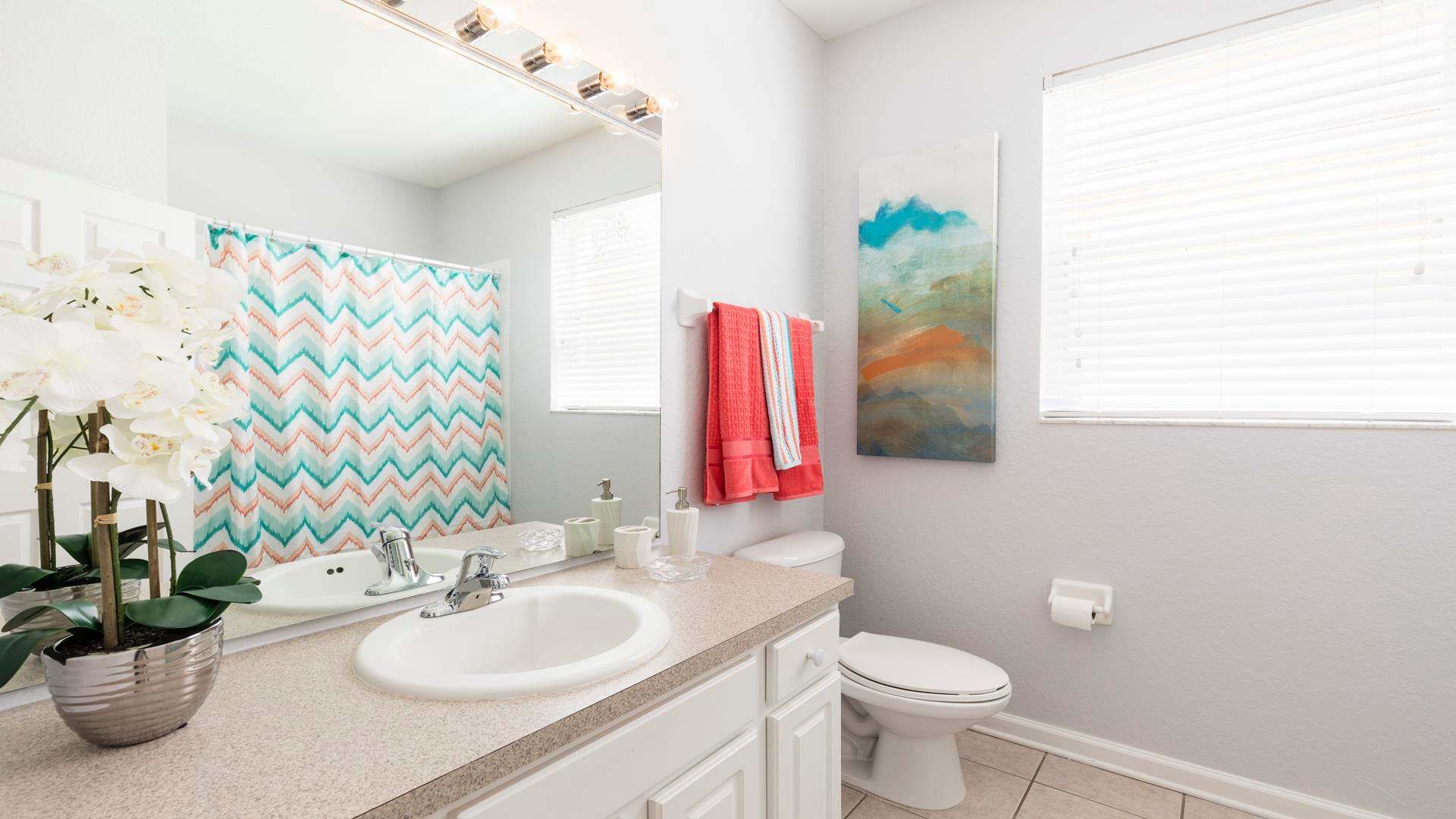 Bright and modern bathroom with colorful accents, natural light, and stylish decor.