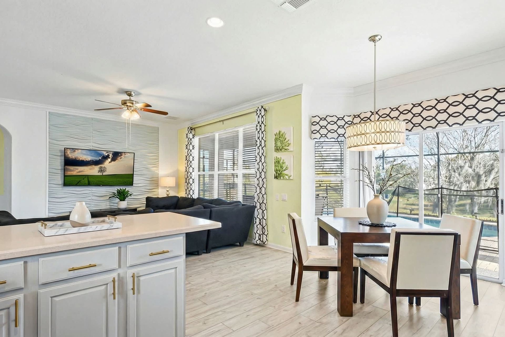 Bright open kitchen and living area with pool views and cozy seating.