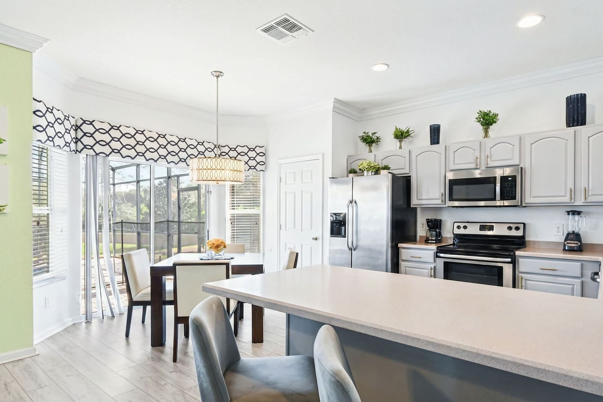 Bright open kitchen with breakfast bar, stainless appliances, and poolside views.