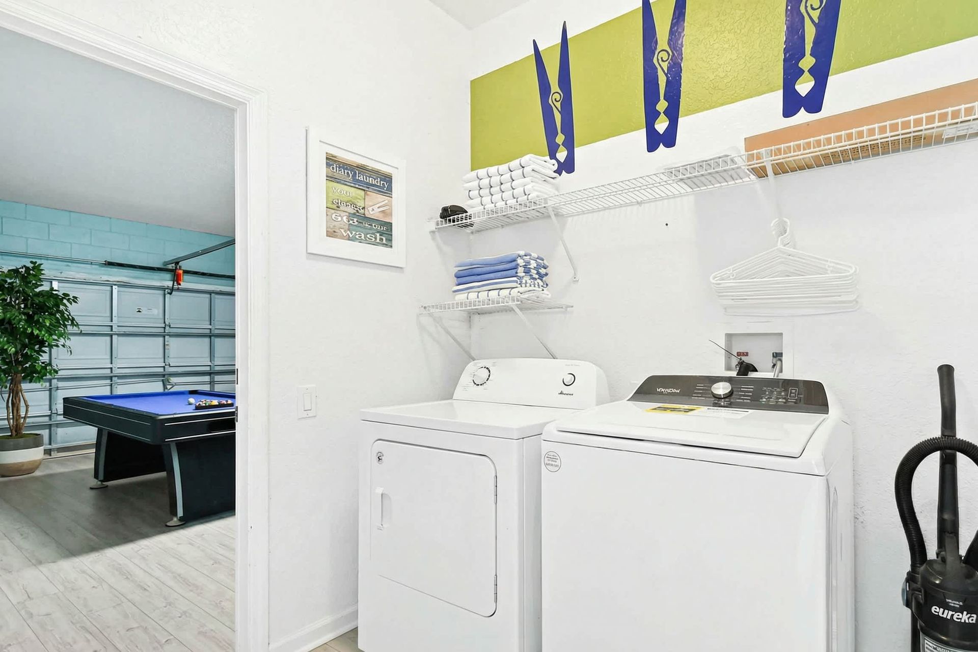Laundry room with modern appliances adjacent to a vibrant game room with pool table.